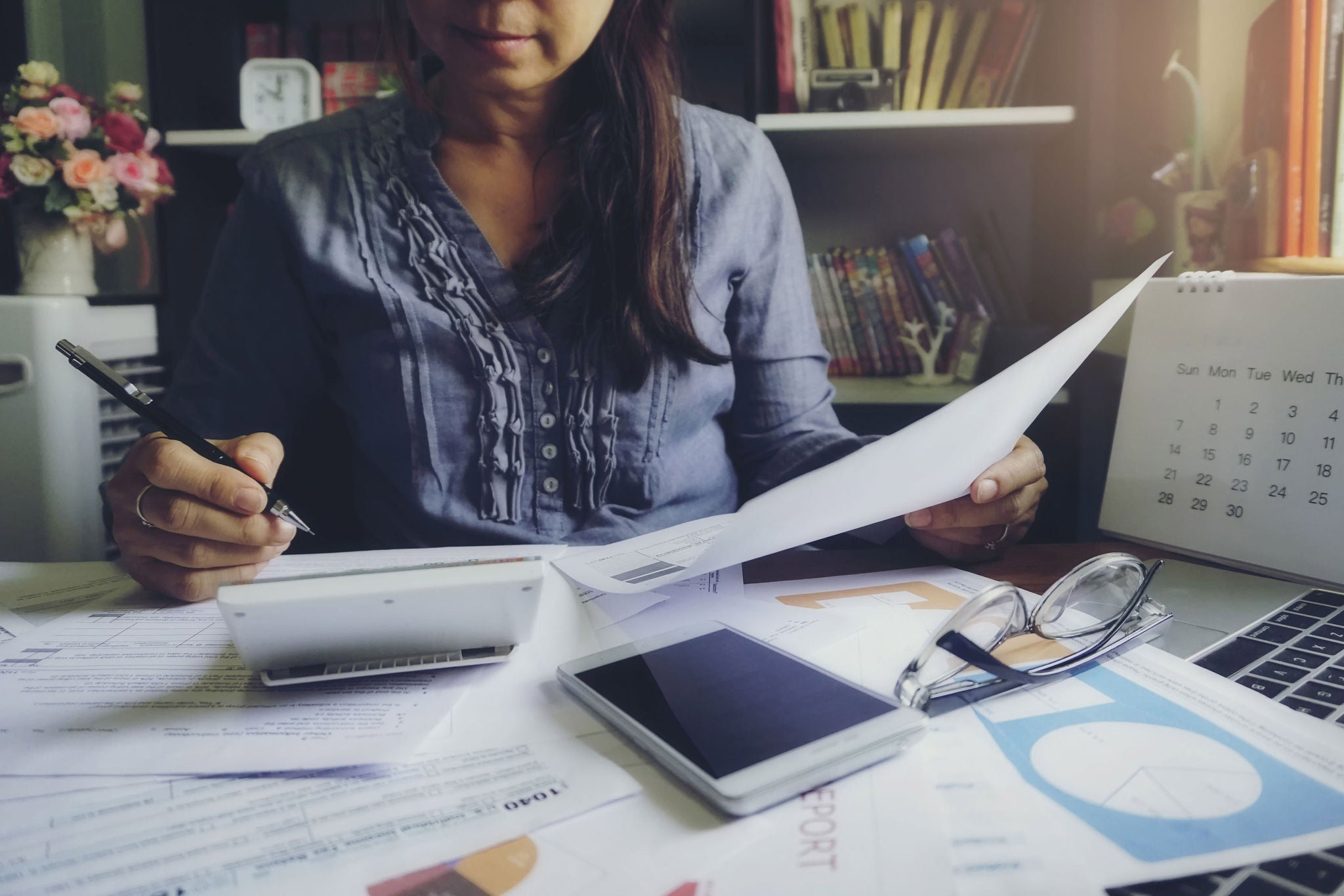 Accountant using calculator on a desk of papers