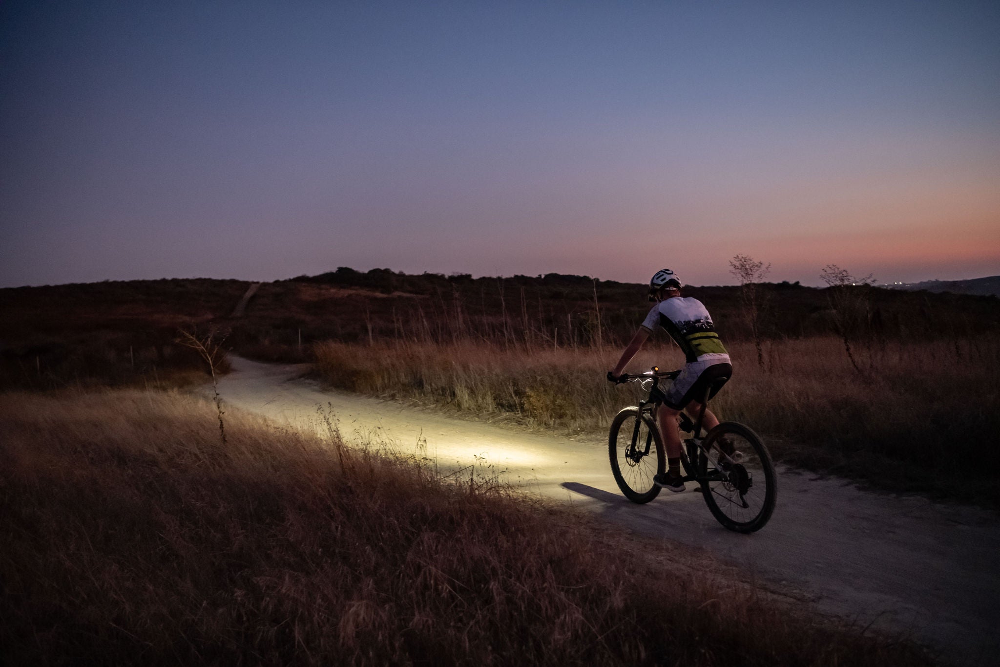 Night MTB Rider With A Light At Sunset