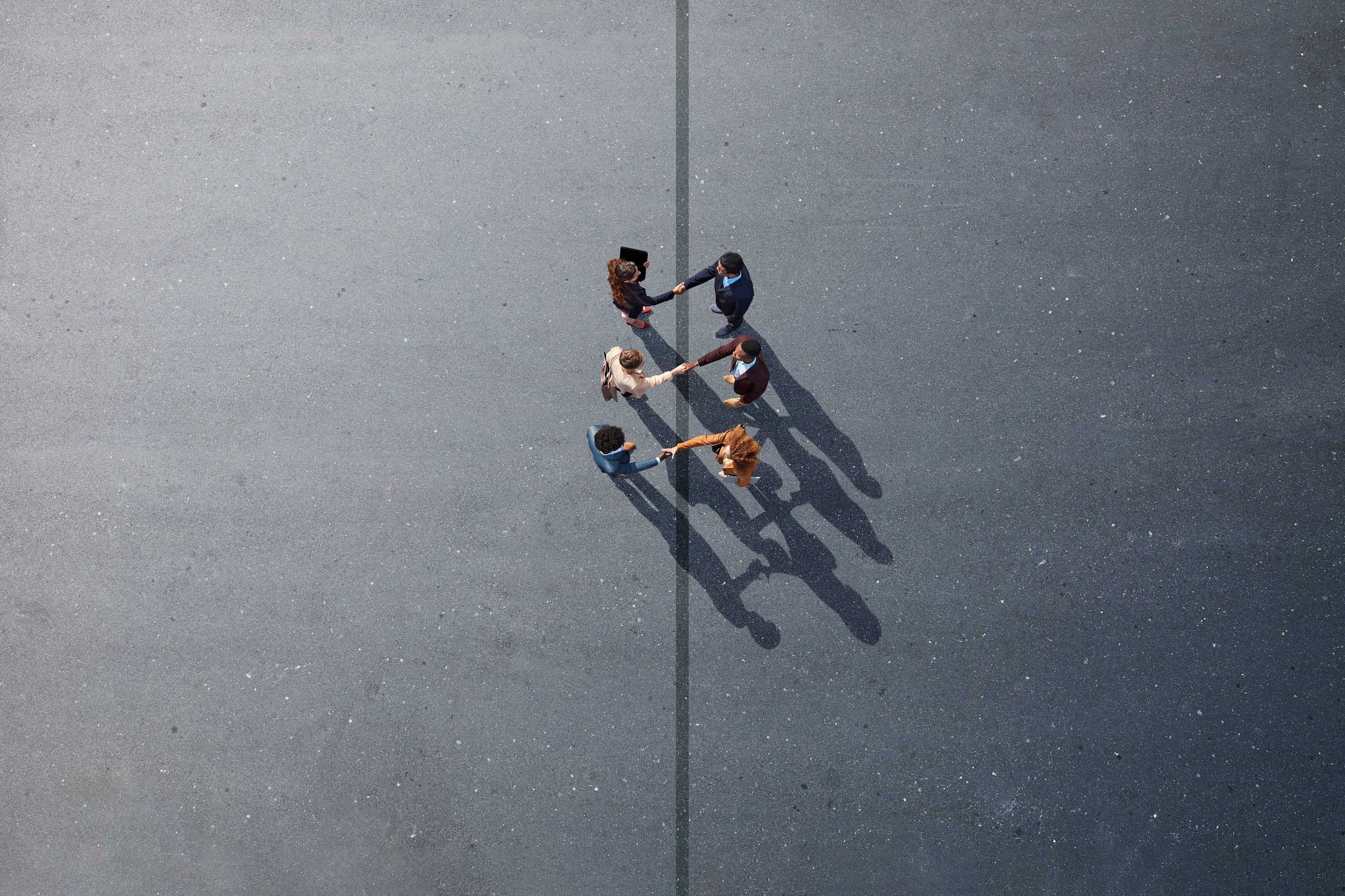 ey-businesspeople-making-handshakes-across-line-on-painted-asphalt.jpg