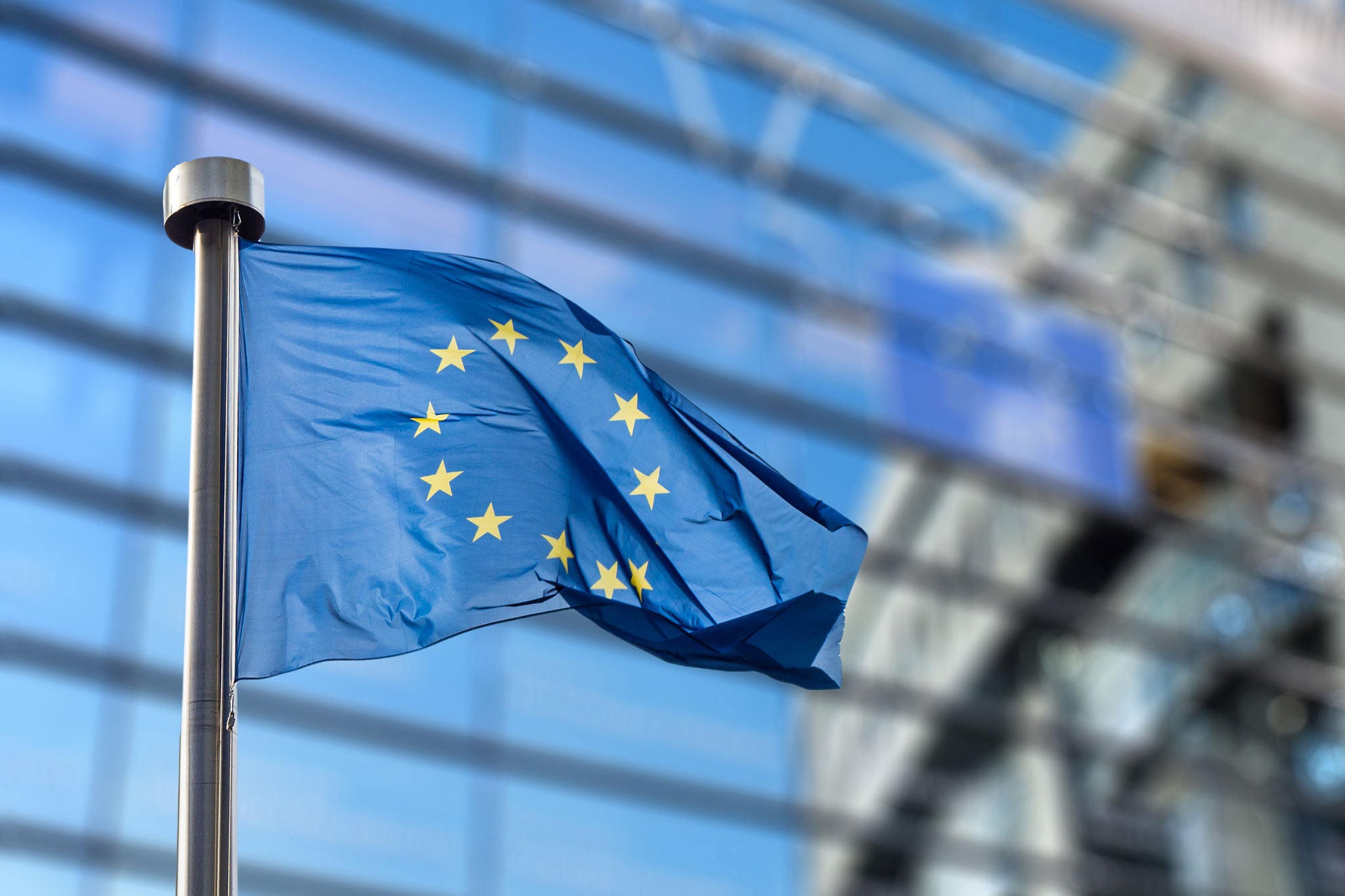 European Union flags in front of the blurred European Parliament in Brussels, Belgium