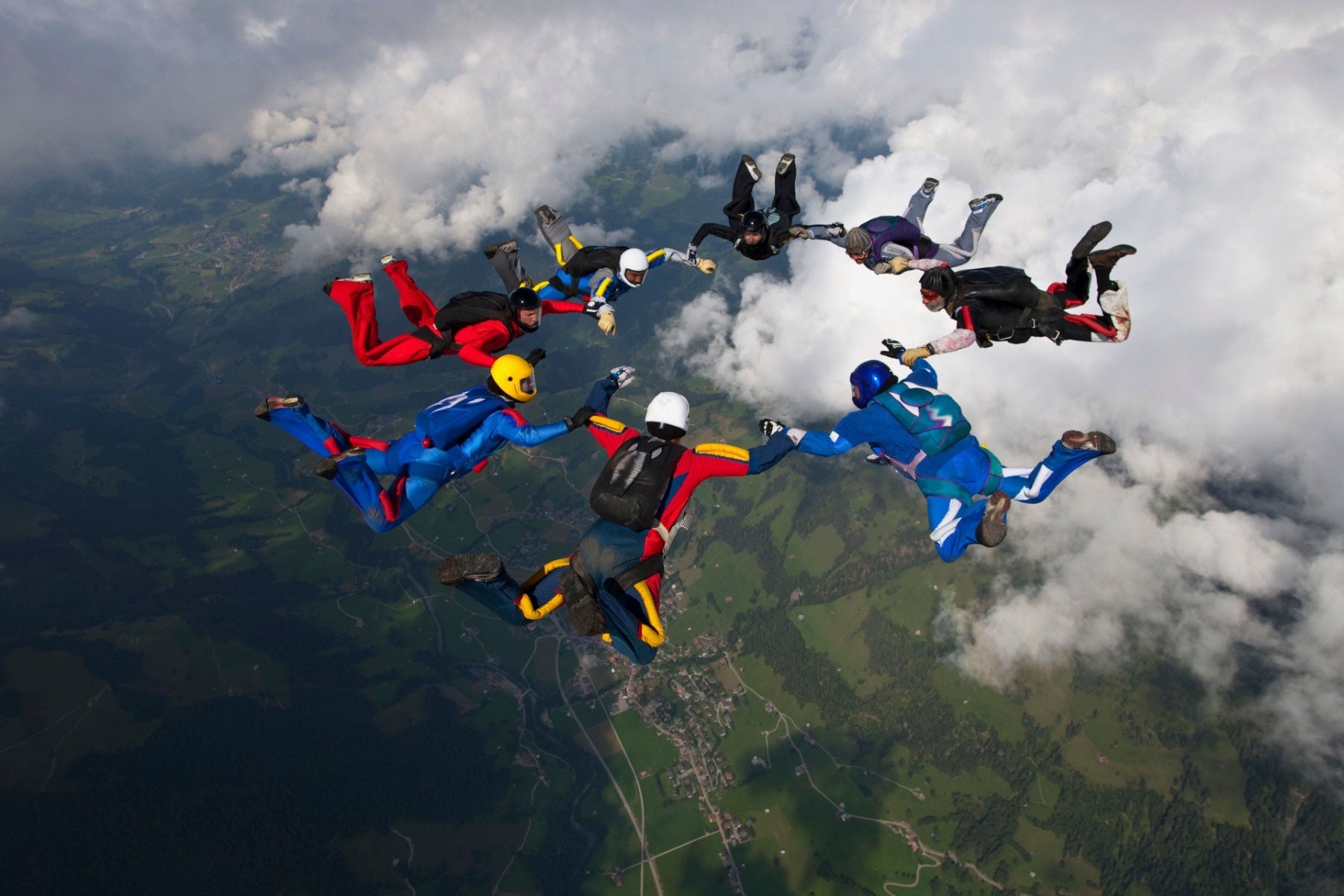 Group of people paraglinder floats in a blue sky dotted with fluffy white clouds