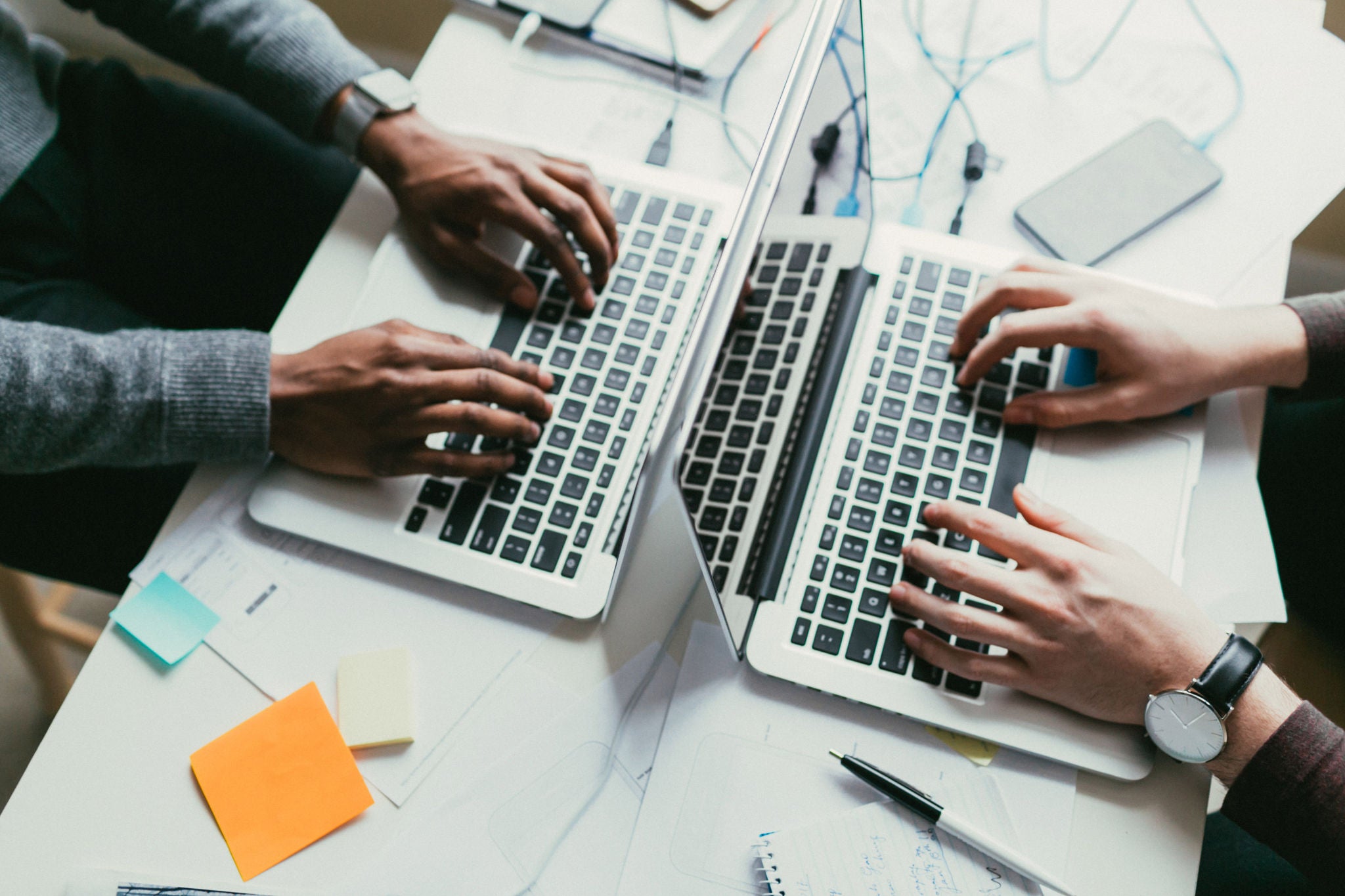 Dos personas usan frente a frente sus laptops