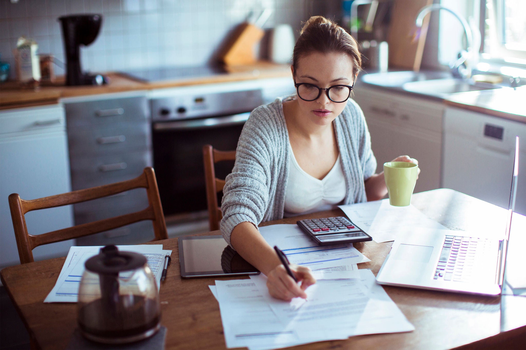 Close up of a young woman doing her bills in the kitchen