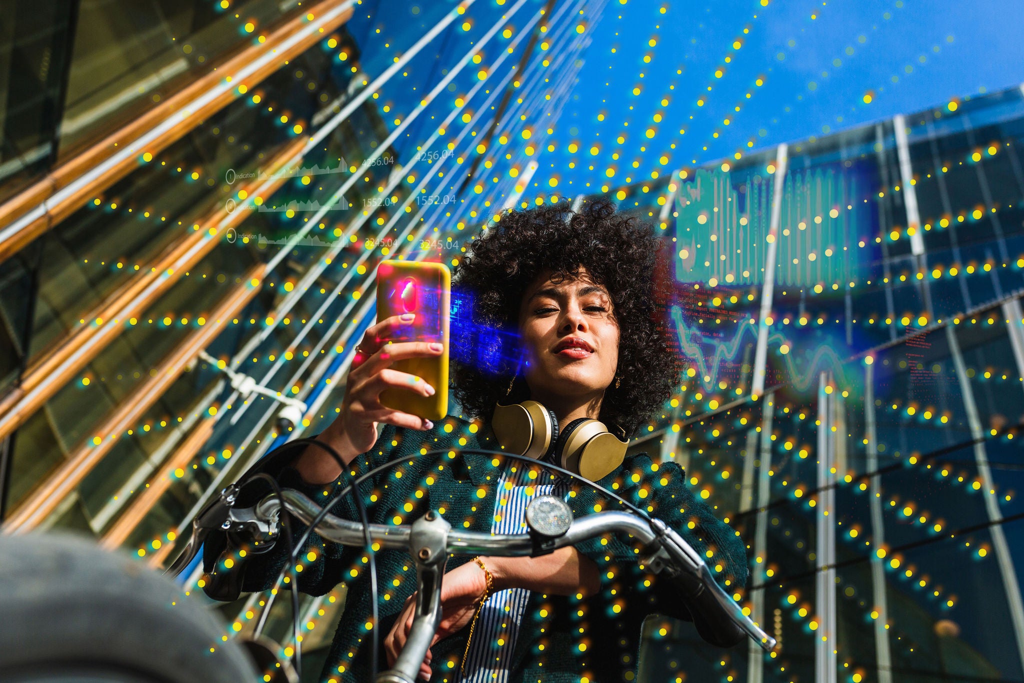 Low angle portrait of woman using a mobile and sitting on a bike in the city