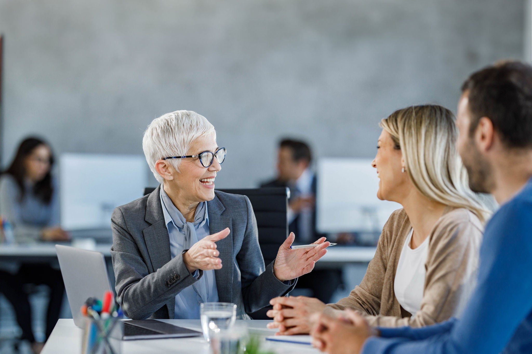 Happy senior agent talking to a couple during a meeting in the office.