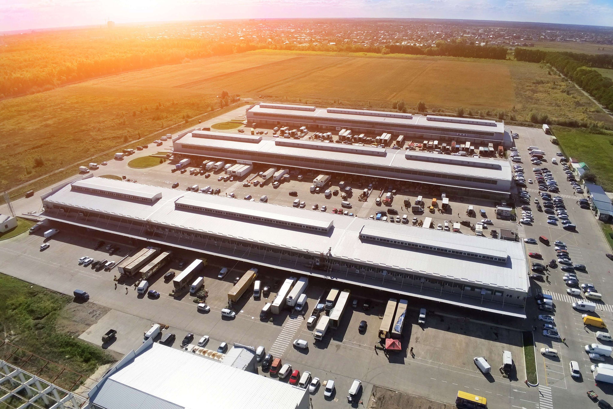 Aerial drone view of group of large modern industrial warehouse or factory buildings in suburban city area.Logistic transportation cargo terminal.