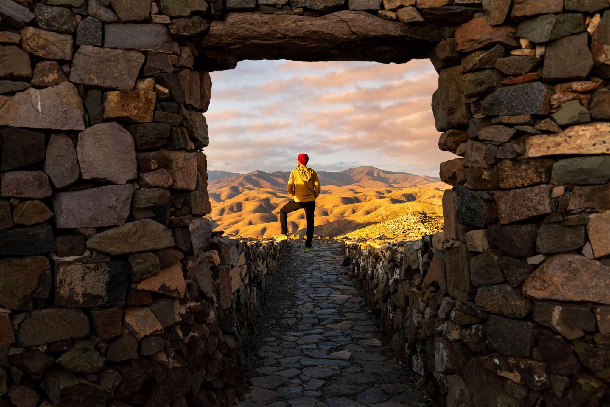 Hiker man admiring the volcanic landscape from stone path of Sicasumbre viewpoint, Fuerteventura, Canary Islands, Spain