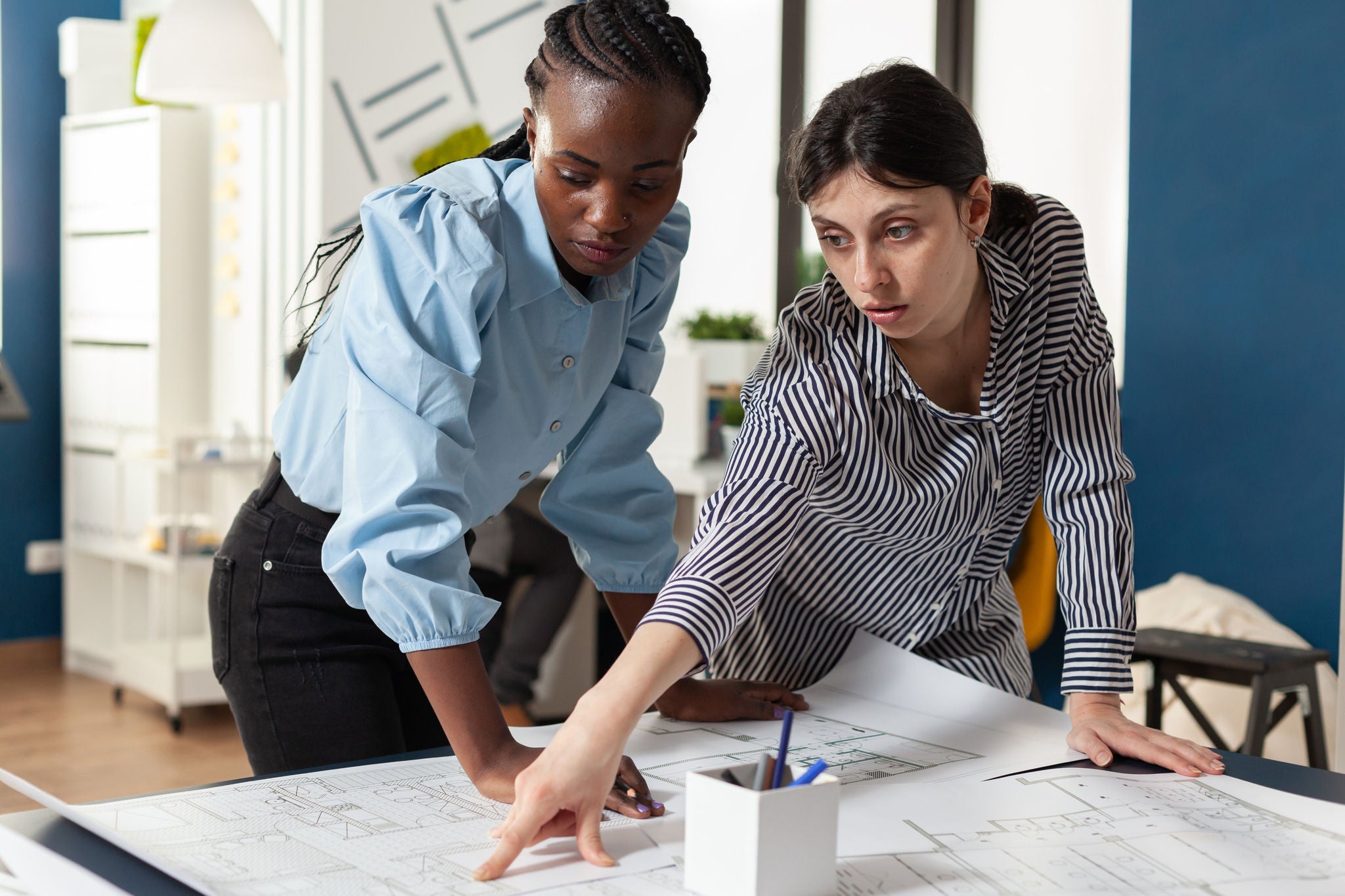 Two ladies were discussing about design on blueprint paper