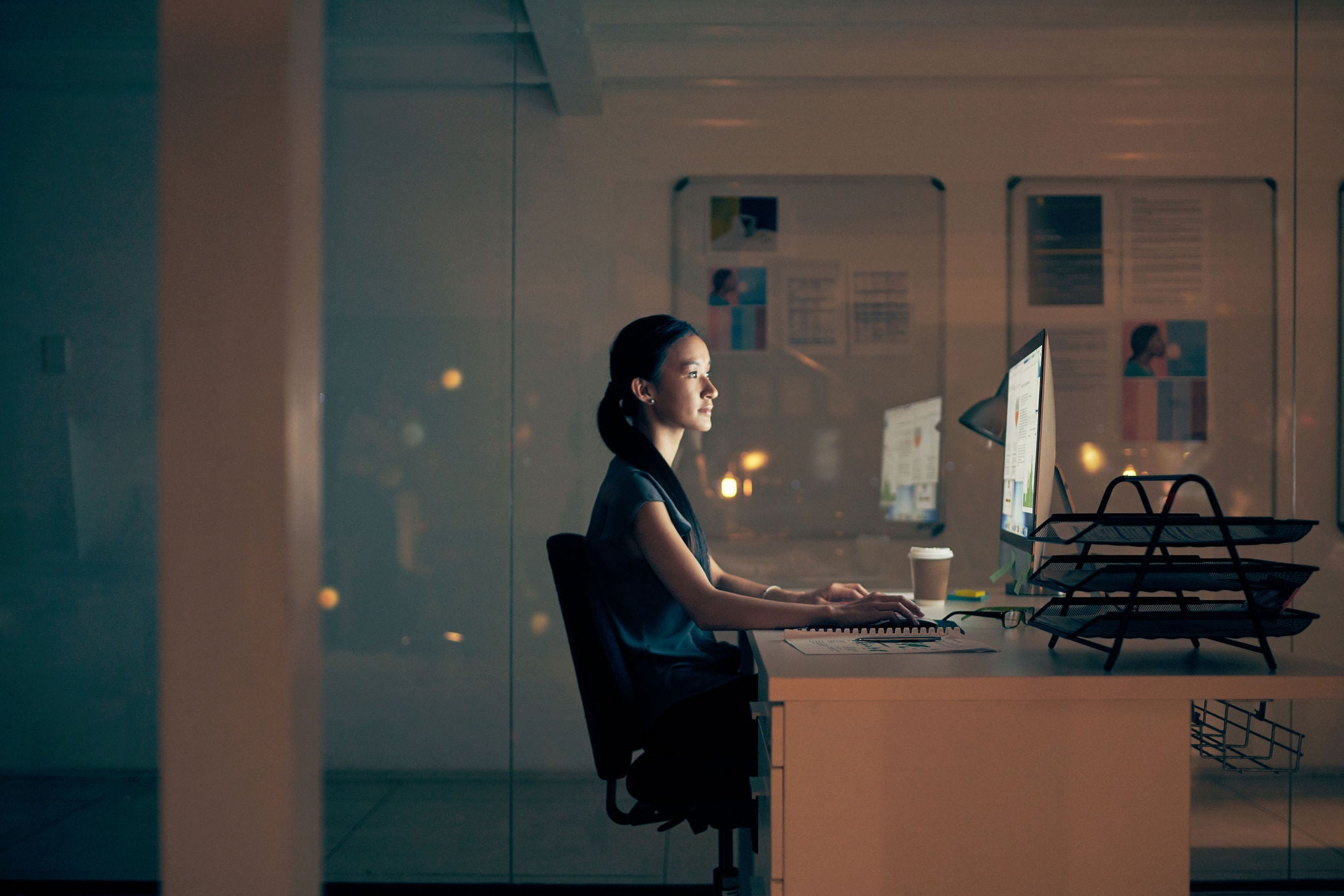 Shot of a young businesswoman using a computer at night in a modern office