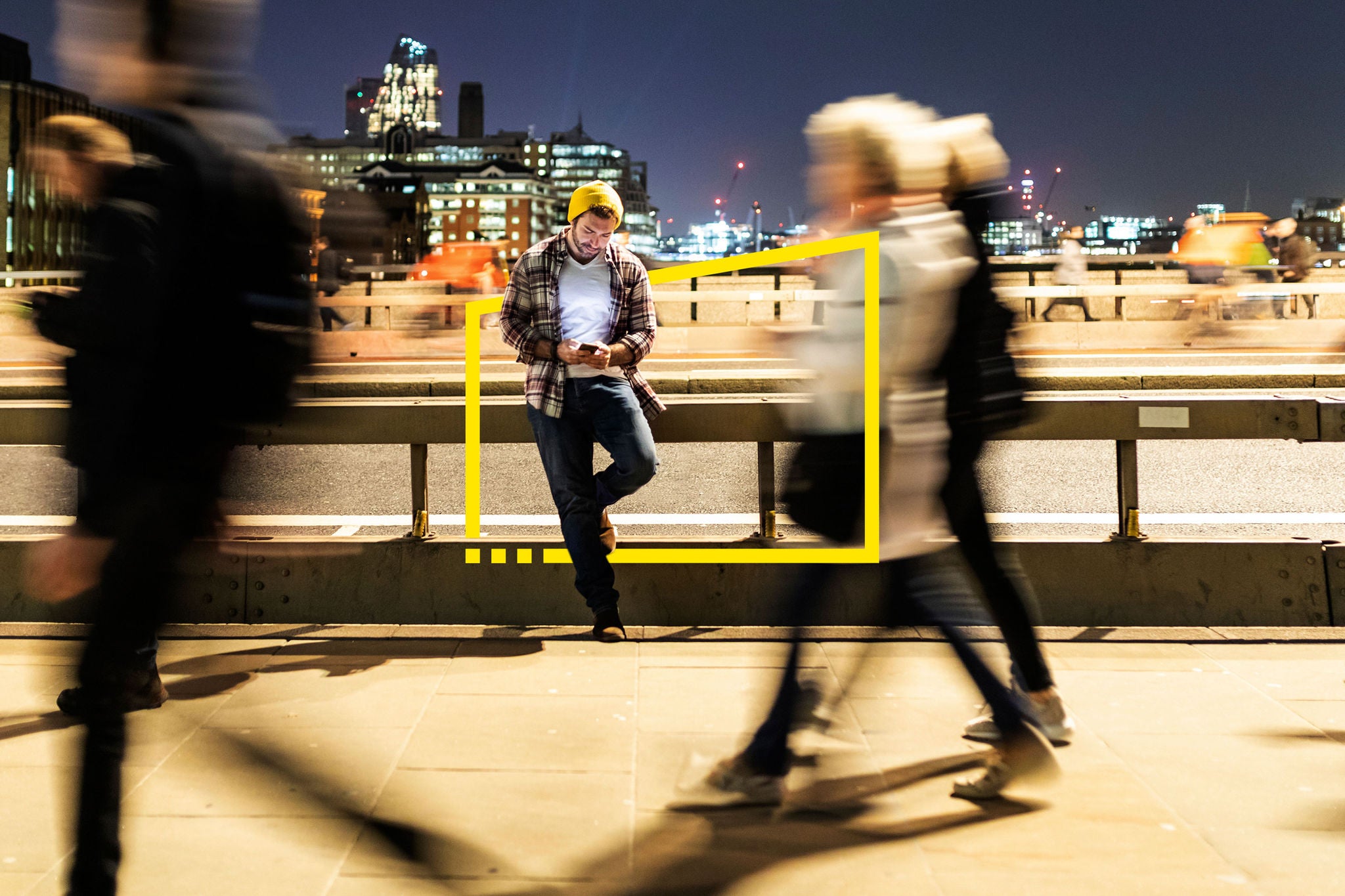 UK, London, man looking at his phone with blurred people walking on the pavement