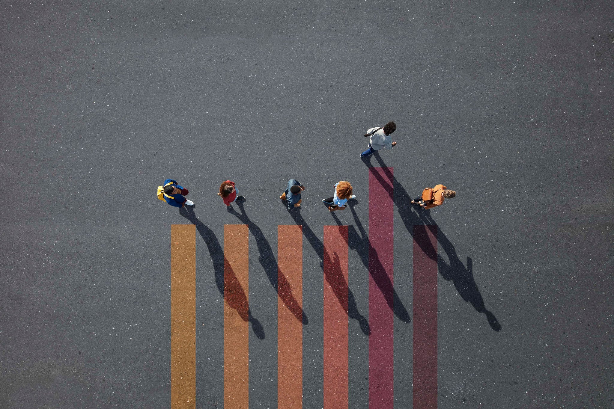 Group of young adults, photographed from above, on various painted tarmac surface, at sunrise.