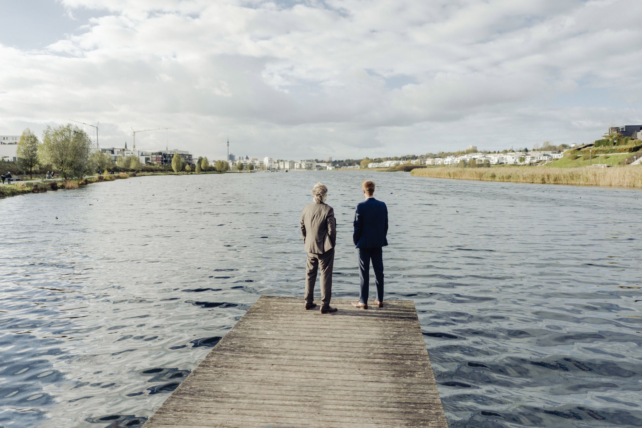 Two businessmen standing on jetty at a lake