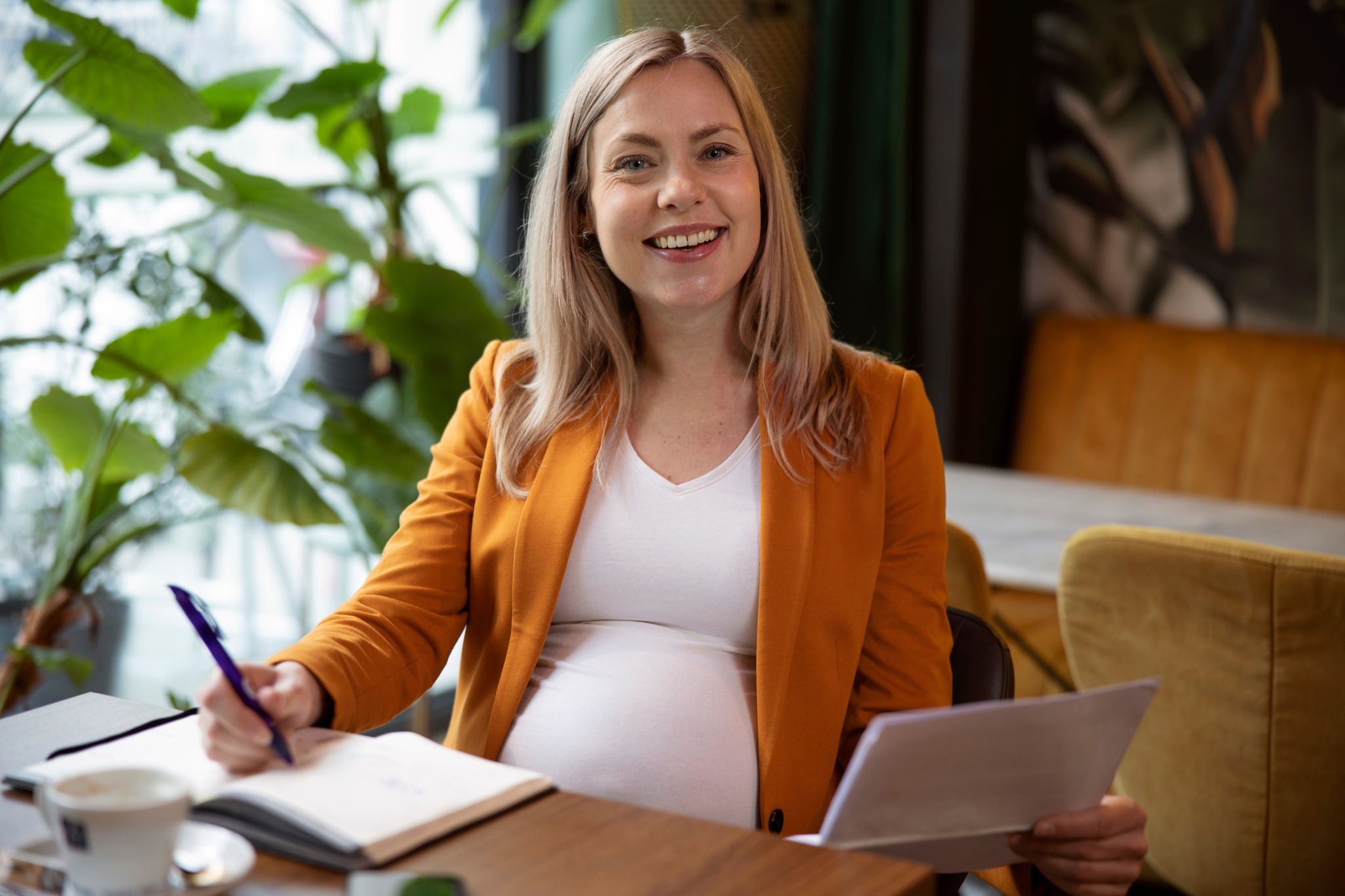 A pregnant lady is writing on note book