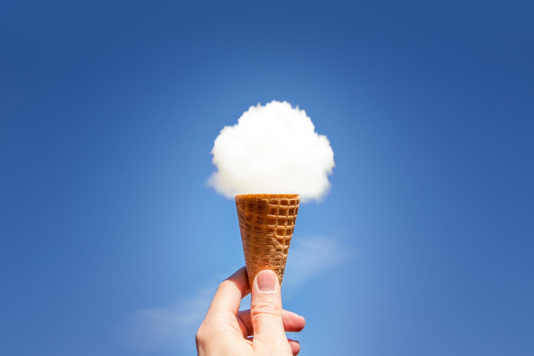 Creative picture of guy holding ice cream cone in the sky with round cloud on the top of cookie cornet.