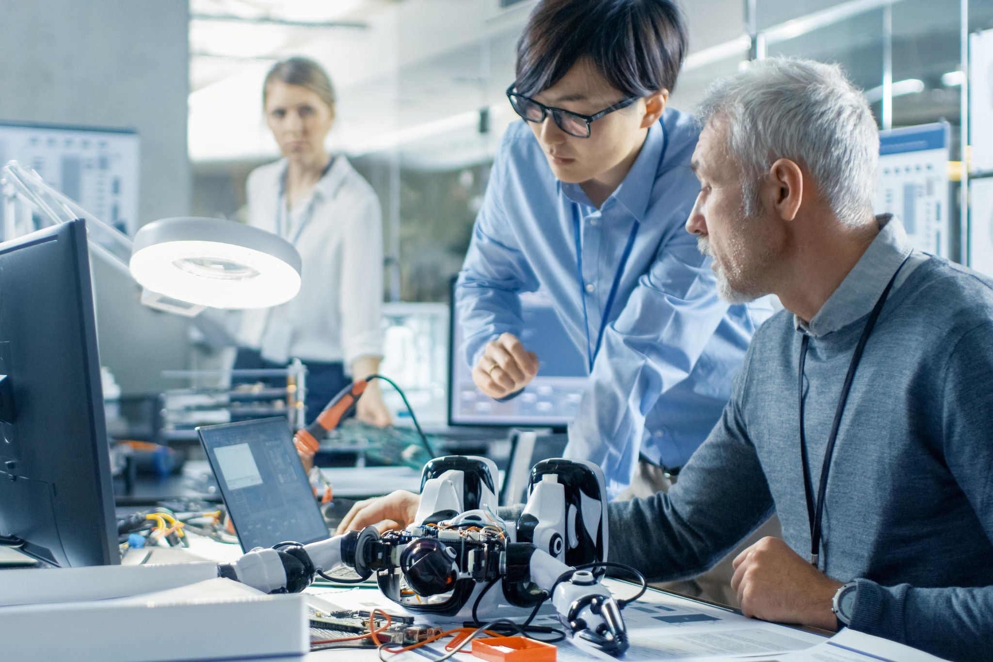 Two engineers talking while working with robot