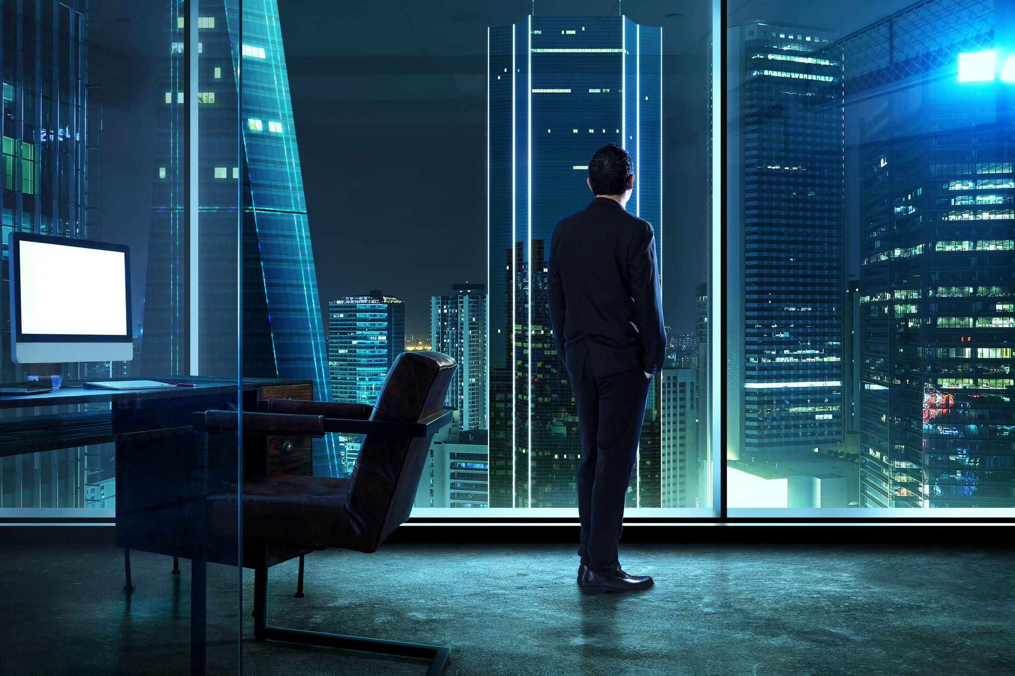 Businessman standing in office watching city night view .