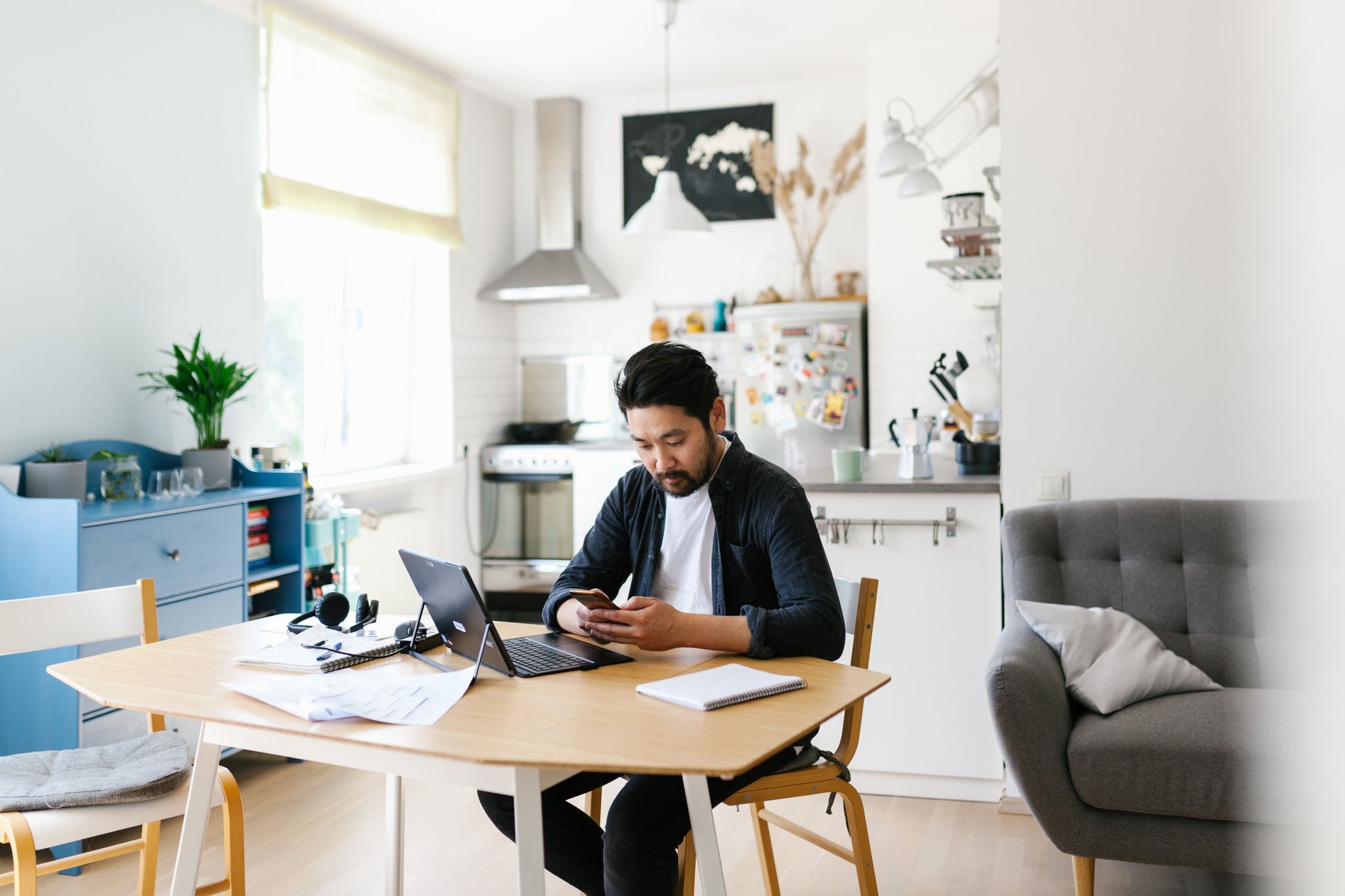 Man sitting on a desk and working on a laptop and mobile