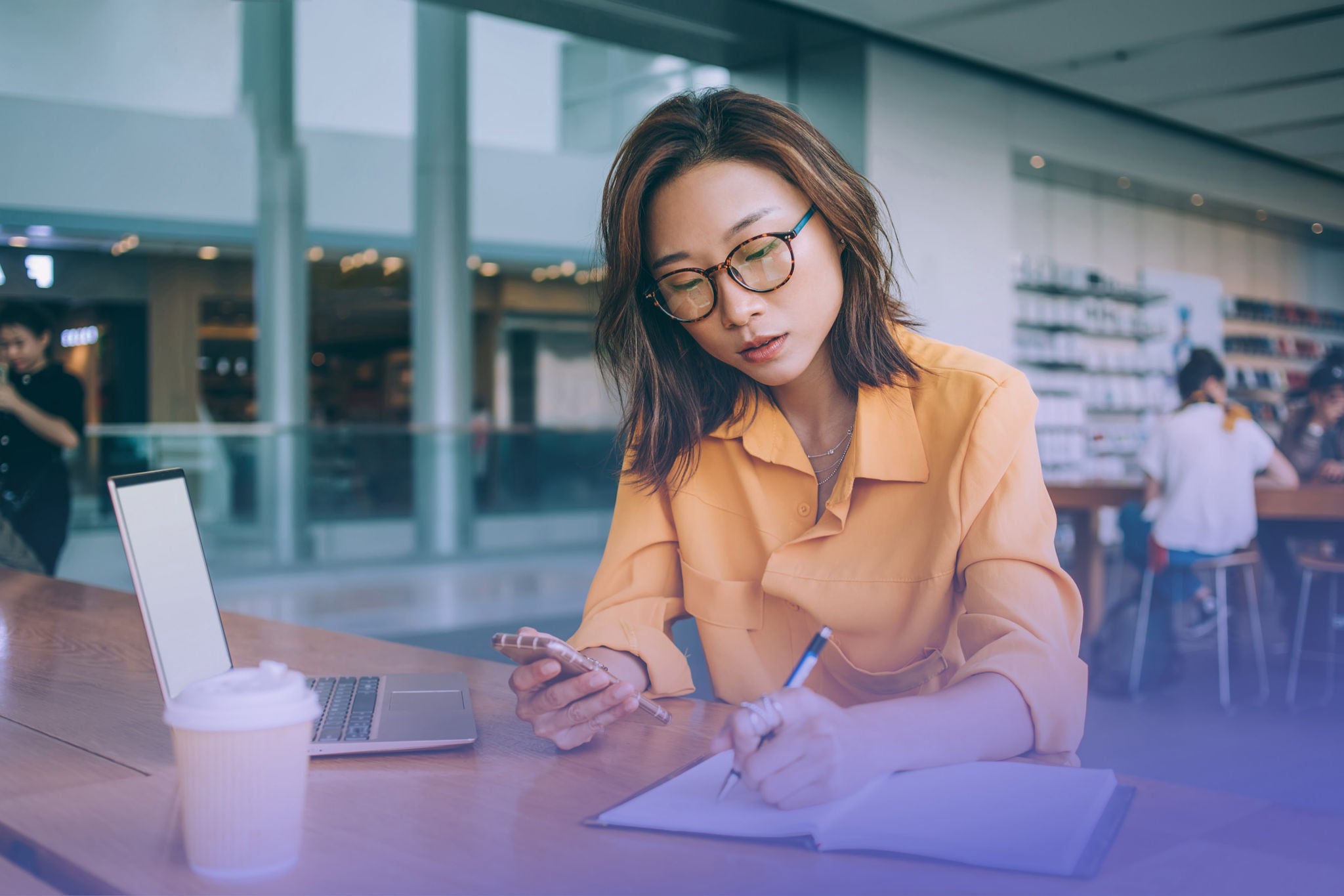 Woman writing notes while browsing on mobile