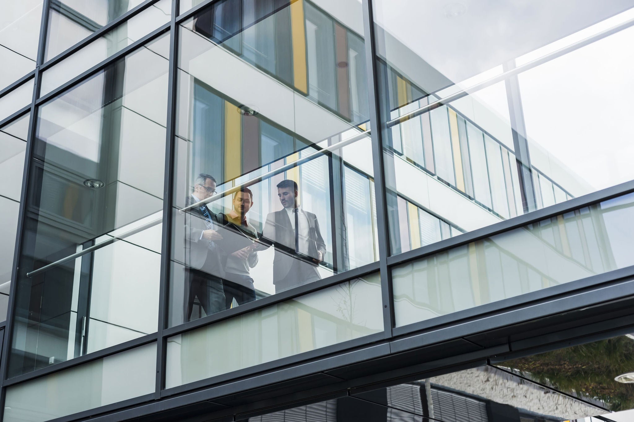 three people walking inside the office building and discussing