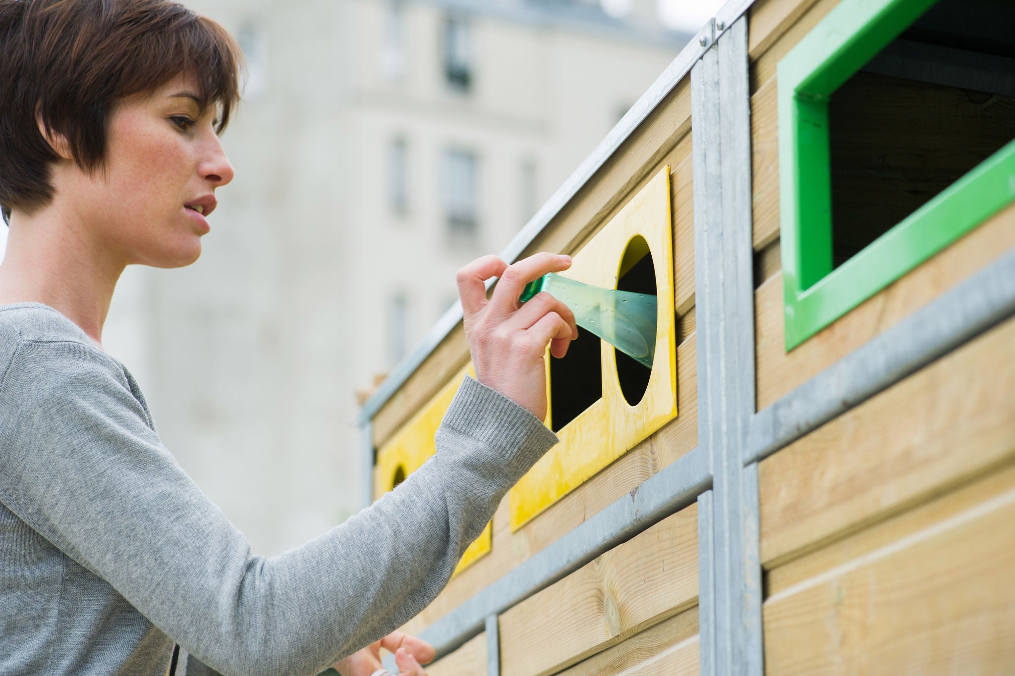 Woman placing plastic bottle in recycling bin