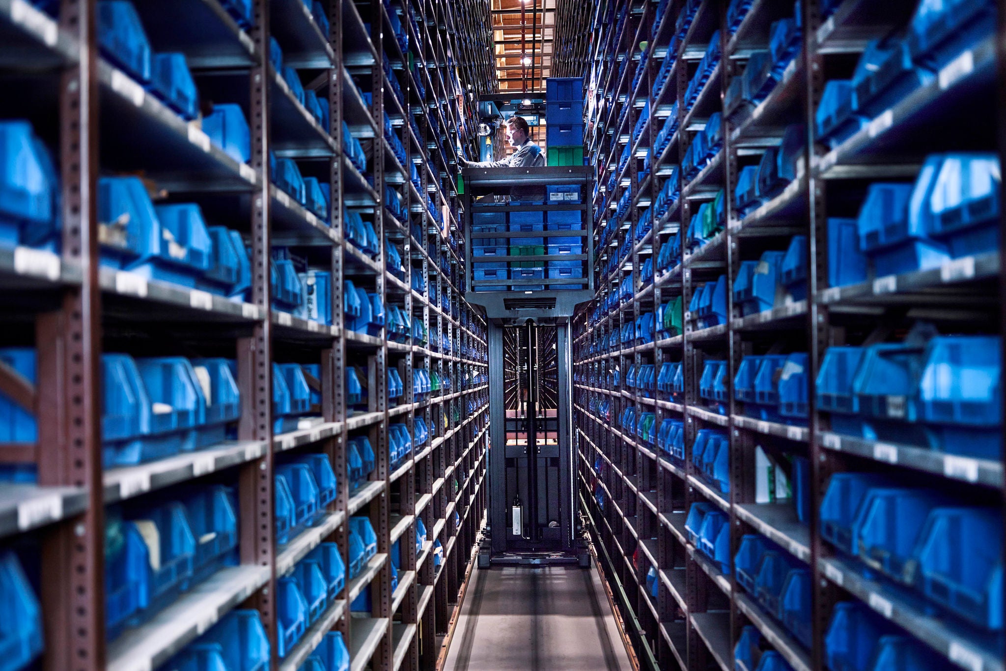 Ey worker operating high rack in storehouse