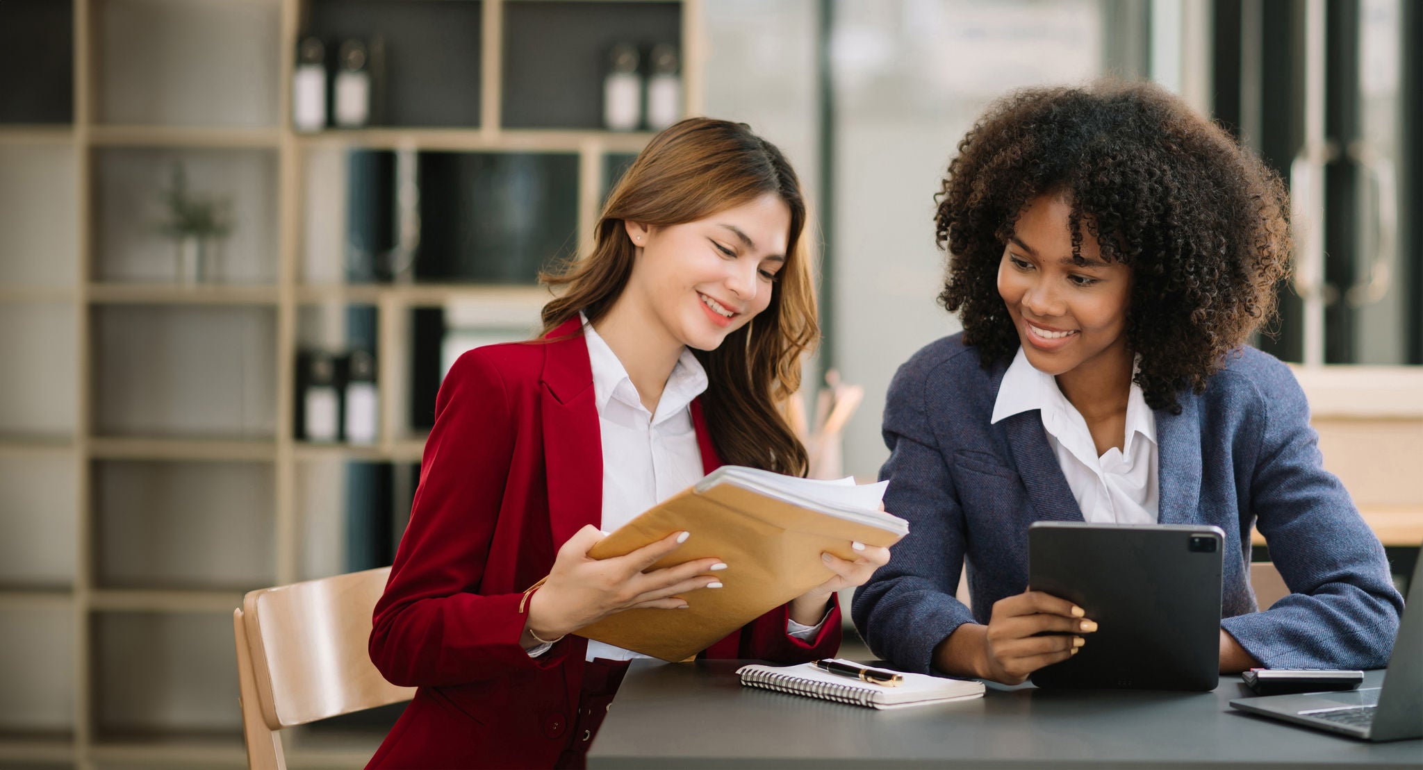 Two Asian businesswoman discuss investment project working and planning strategy with tablet laptop computer in modern office.
