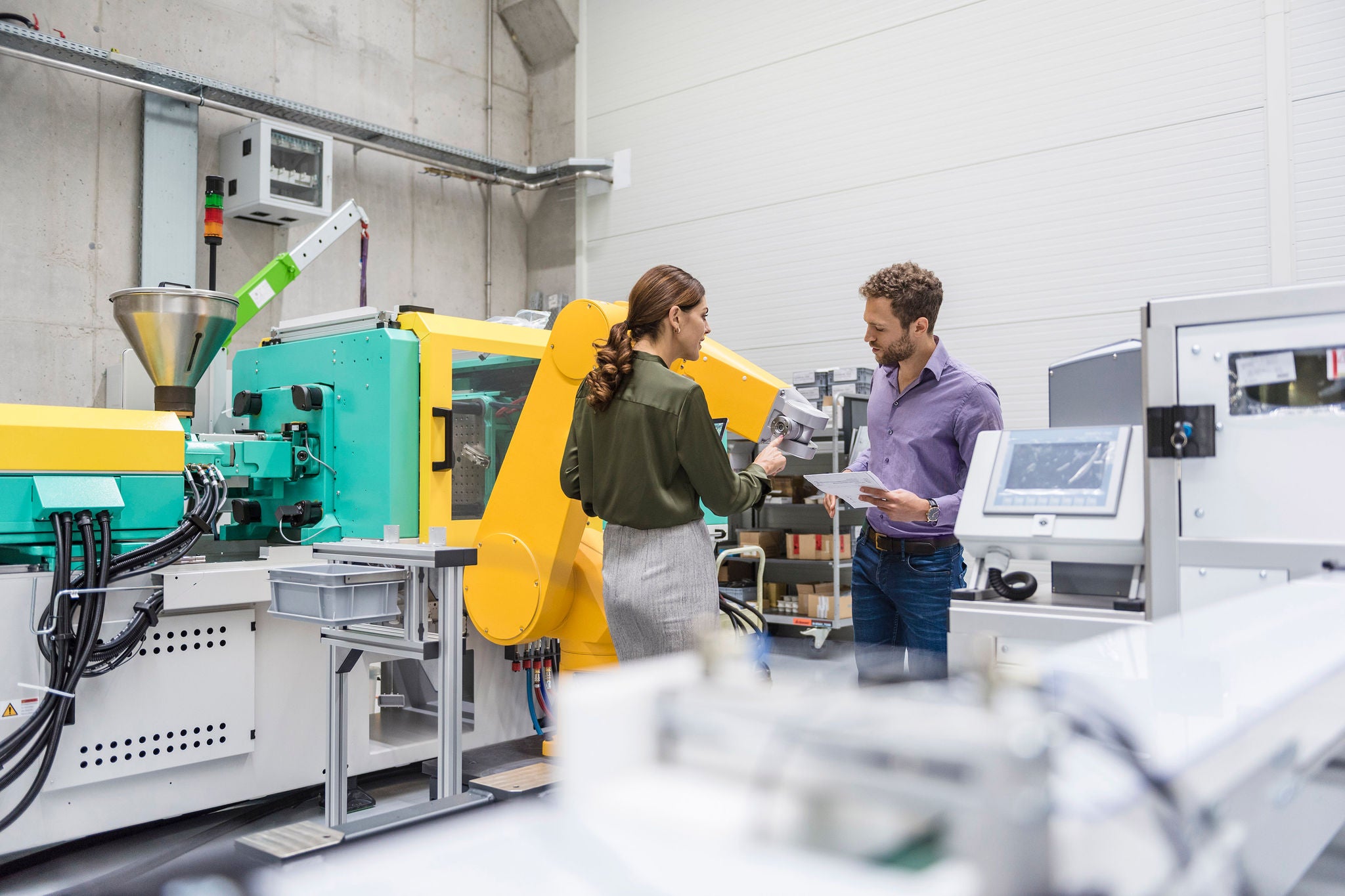 Businessman and woman having a meeting in front of industrial robots in a high tech company