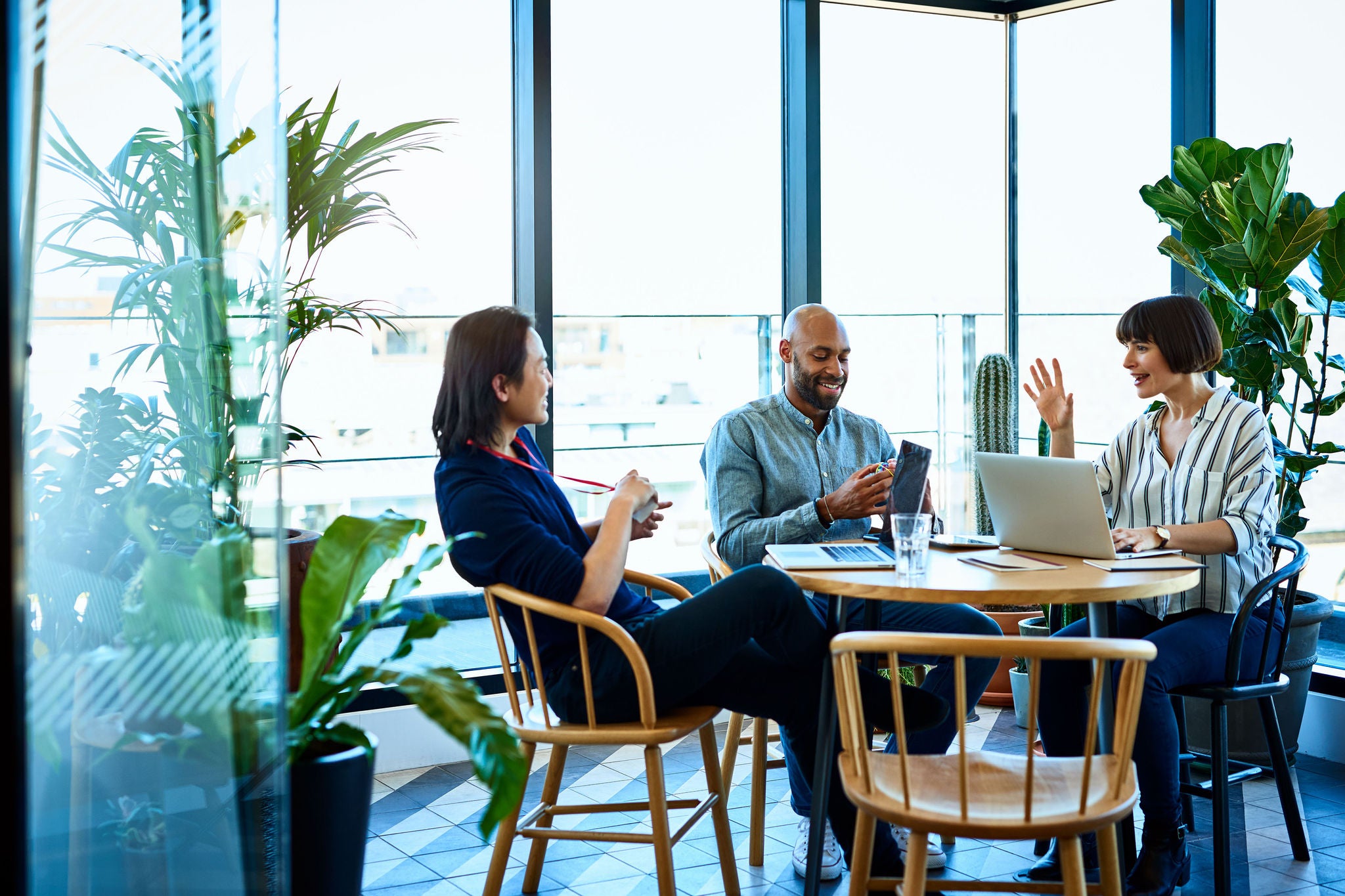 three people sitting around the table and discussing their work progress