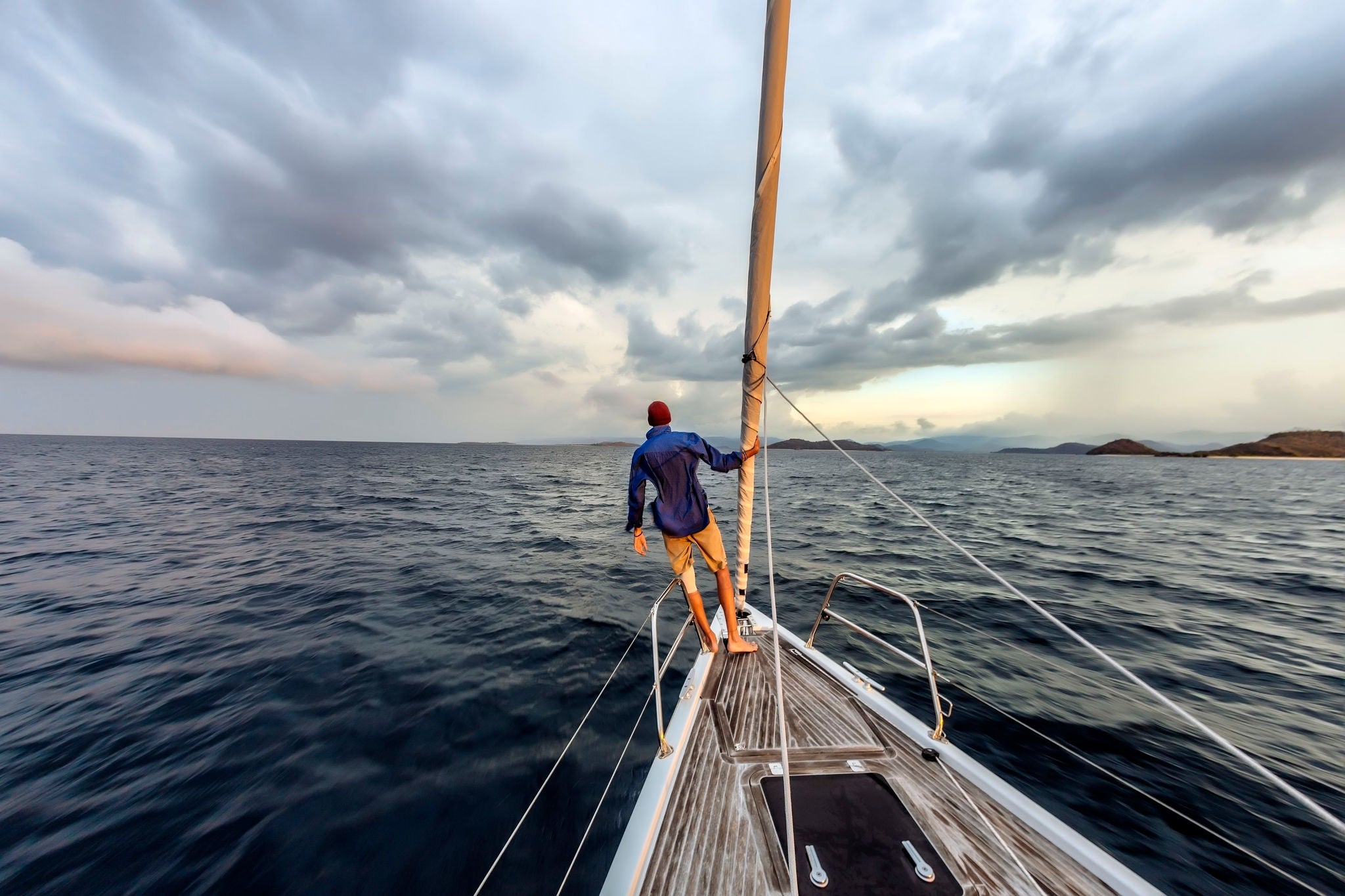 Rear view shot of single man standing on bow of yacht, Lombok, Indonesia