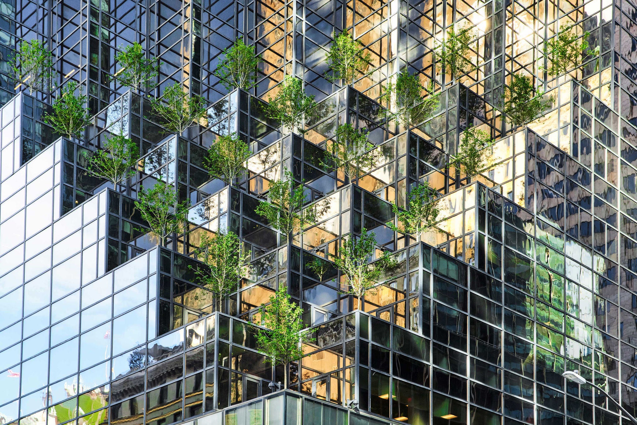 High angle view of a mirrored skyscraper with a modern trees installation on the facade, New York, USA