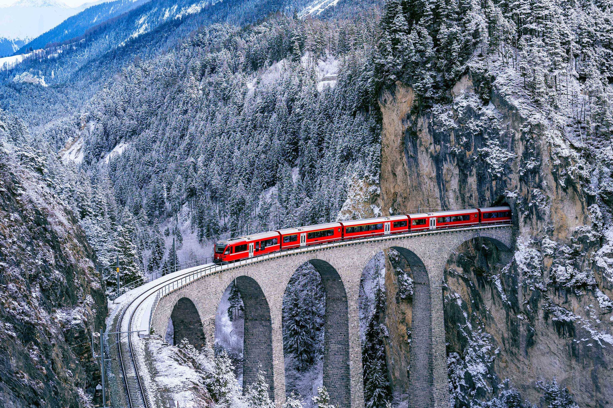 Aerial view of Train passing through famous mountain in Filisur, Switzerland. Landwasser Viaduct world heritage with train express in Swiss Alps snow winter scenery.