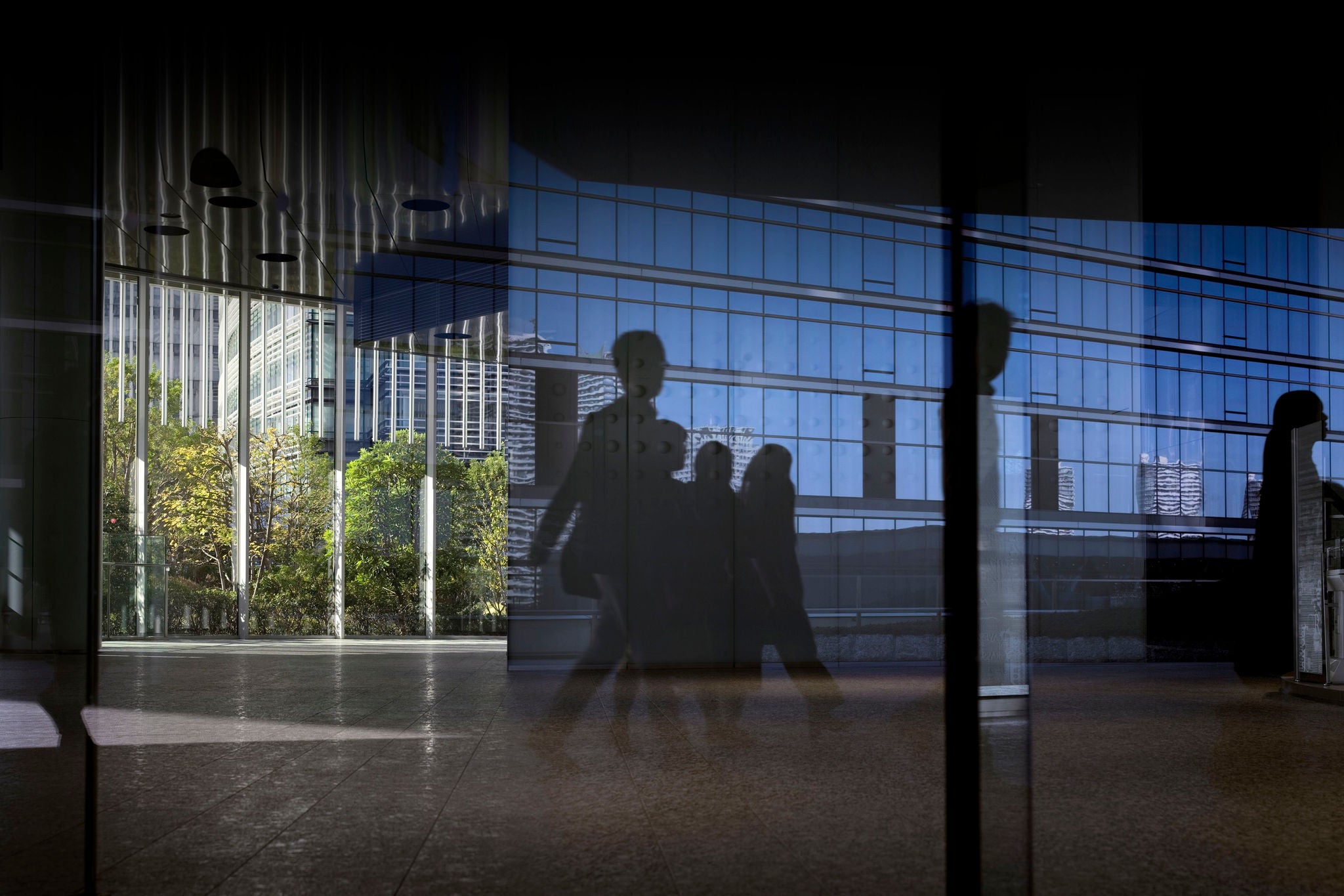 Office window with reflection of office workers arriving for work in Tokyo, Japan at dawn.