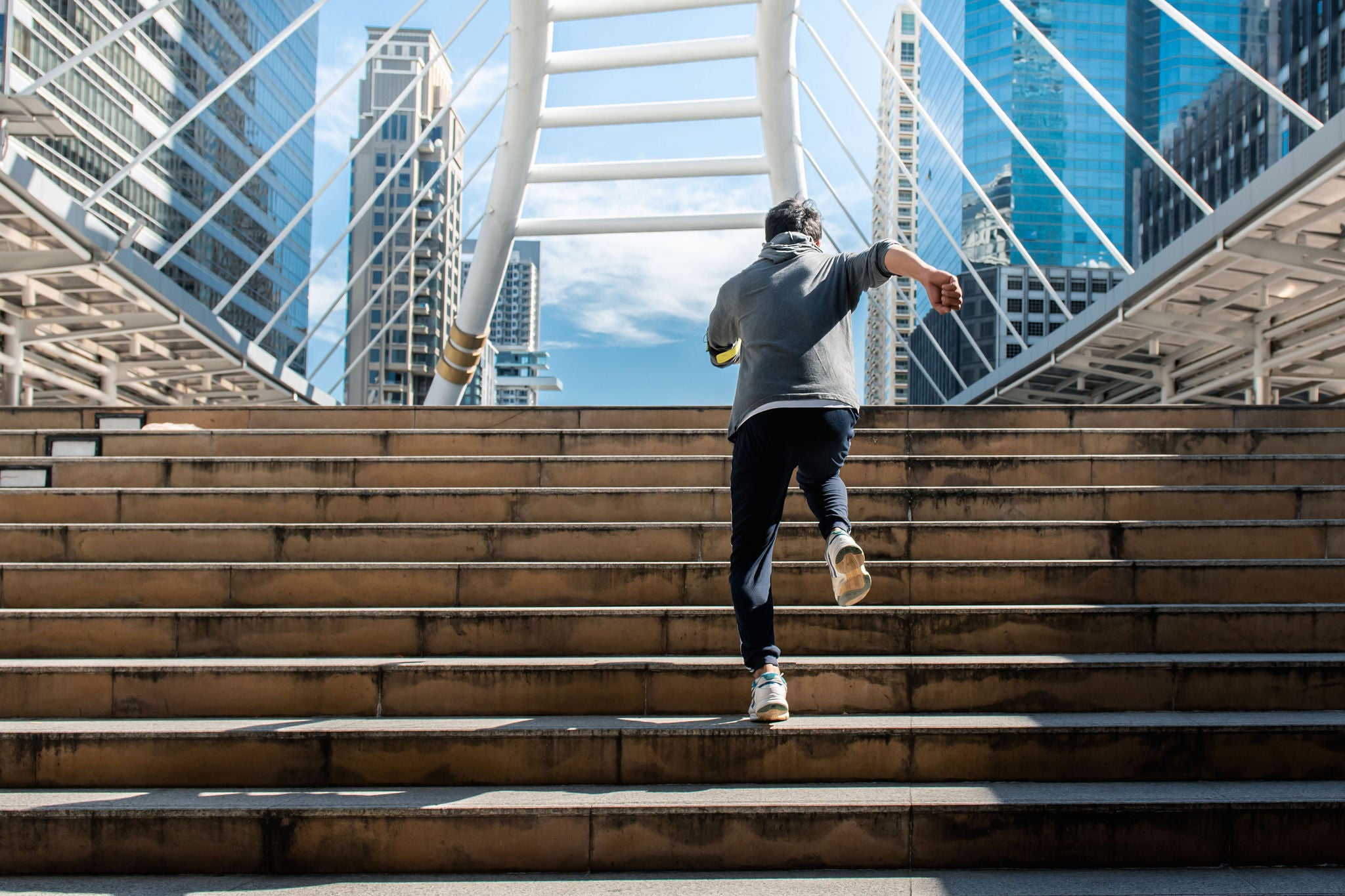 man running up stairs towards bridge