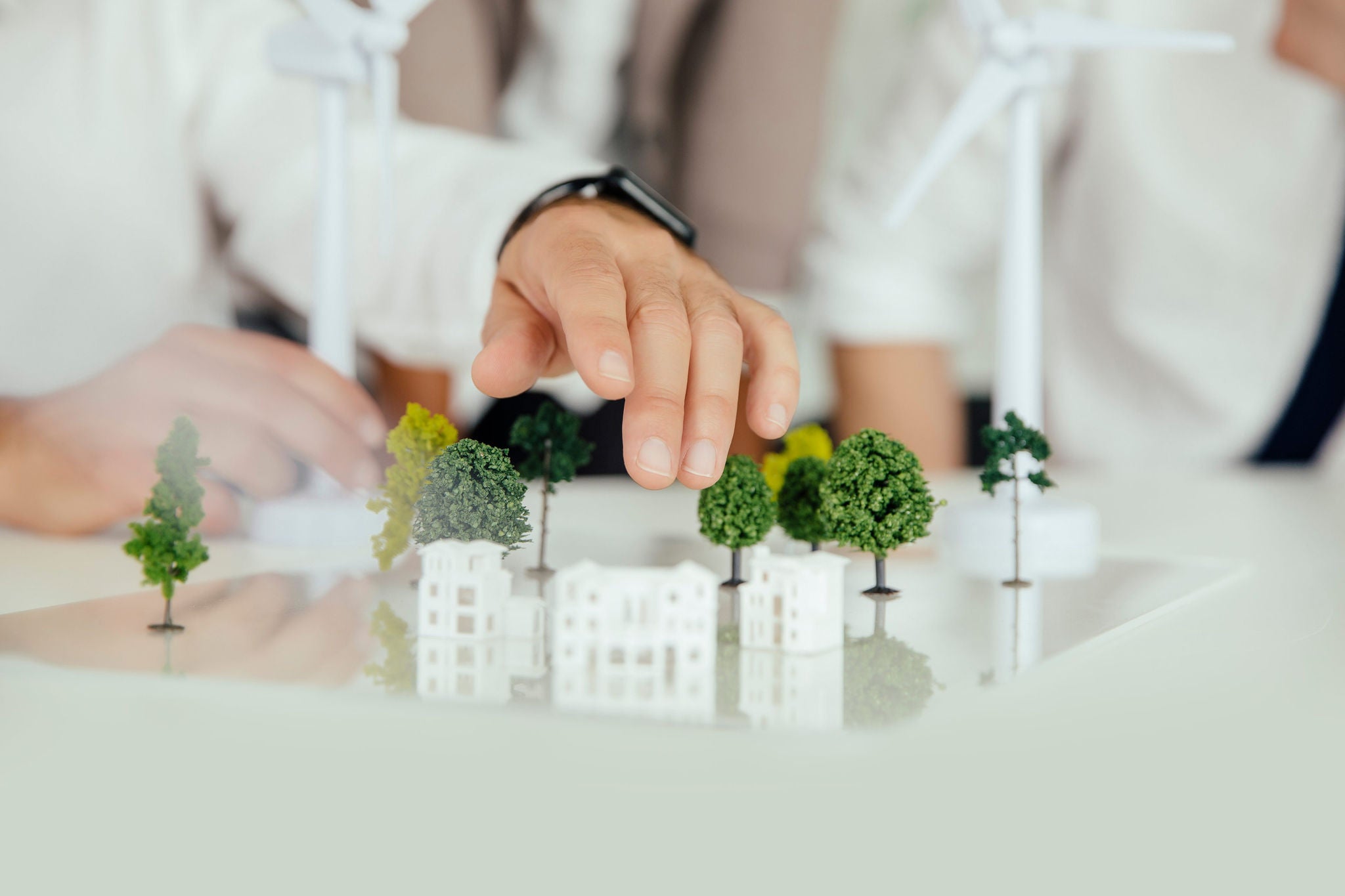 Close-up of business people wind turbine model and houses on conference table