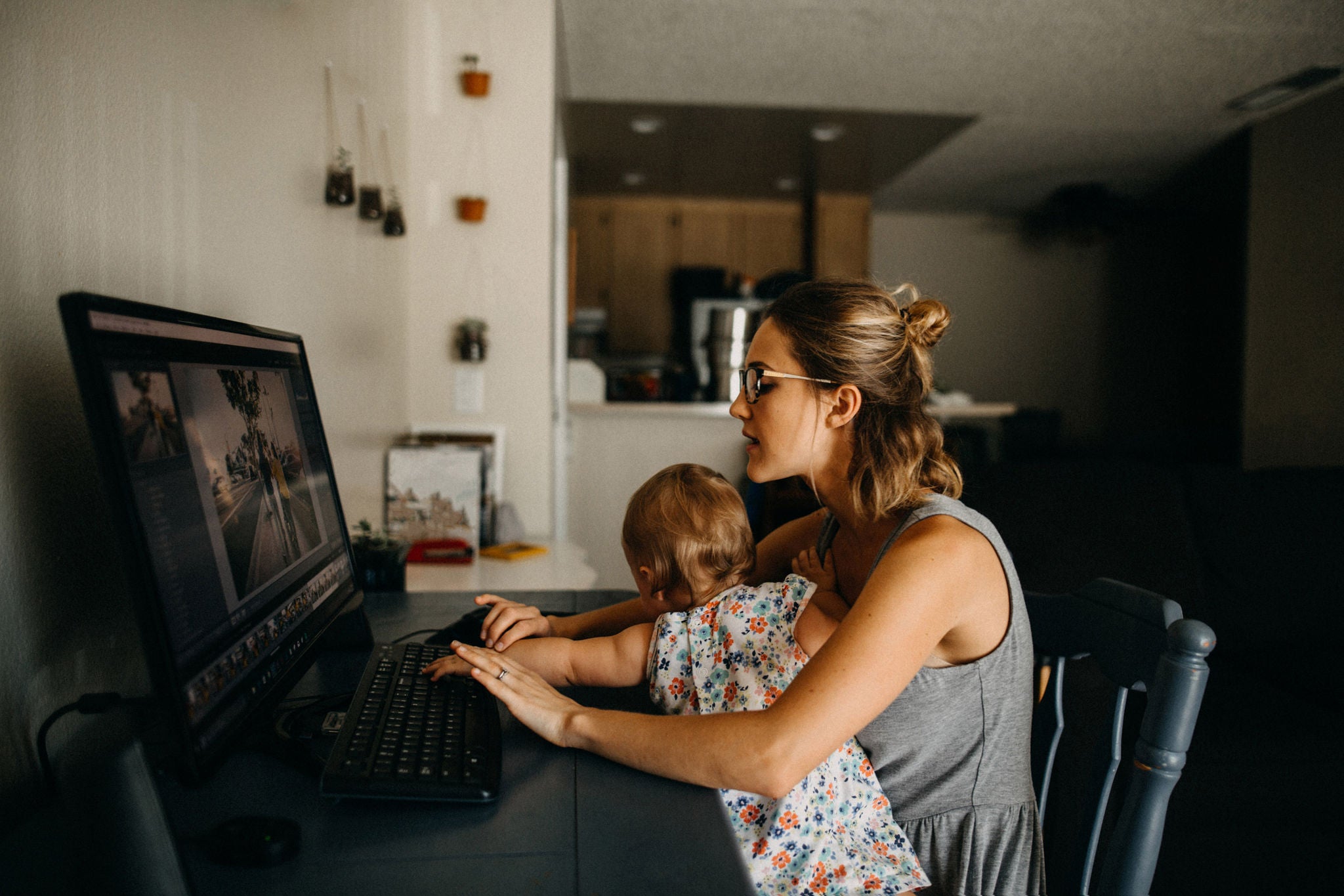 Working mother holding baby and typing on computer