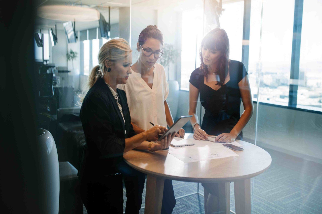 three women are standing and they are discussing about something