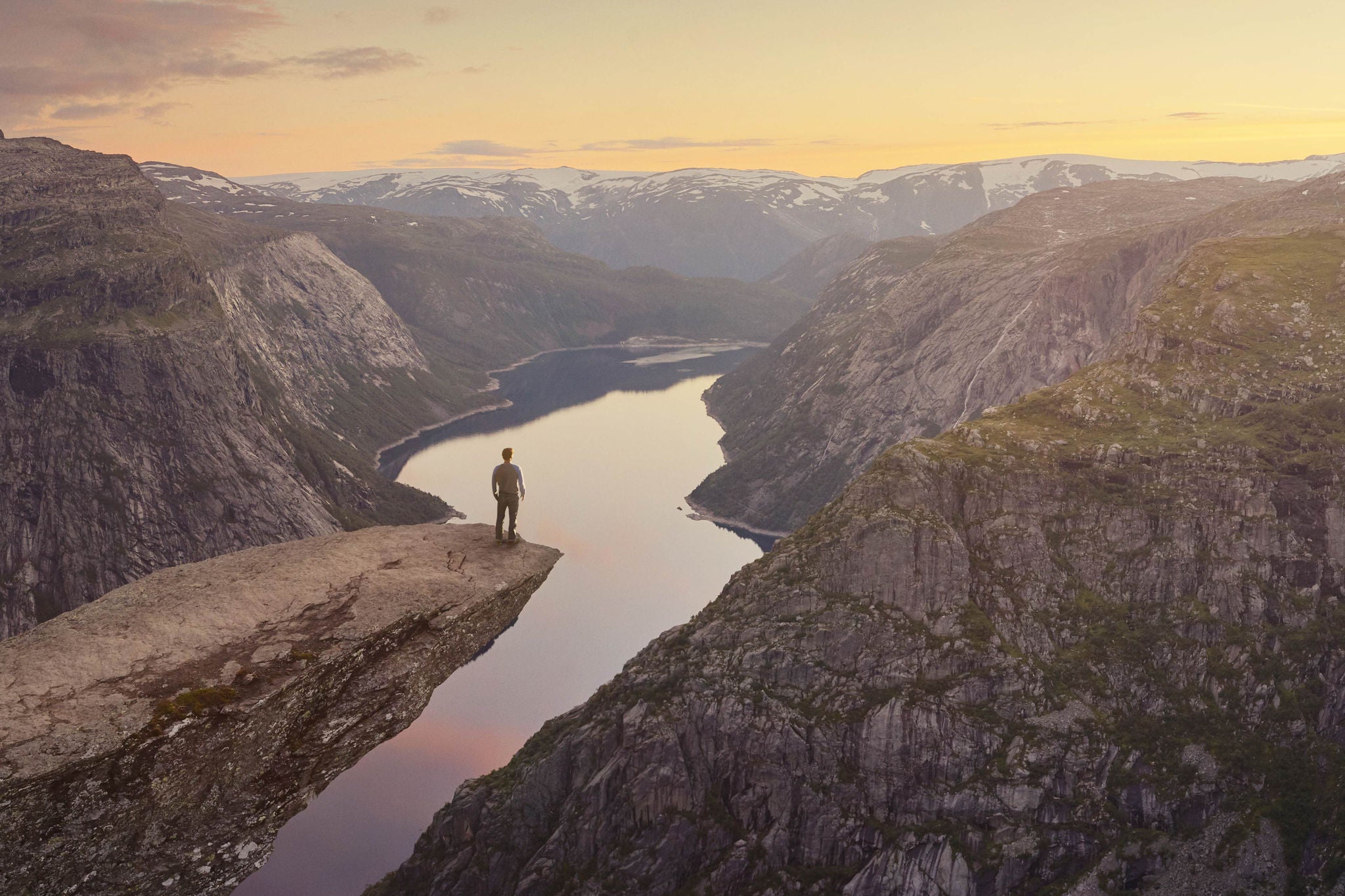 EY Panoramic of traveller looking out at landscape at sunset, Trolltunga, Norway