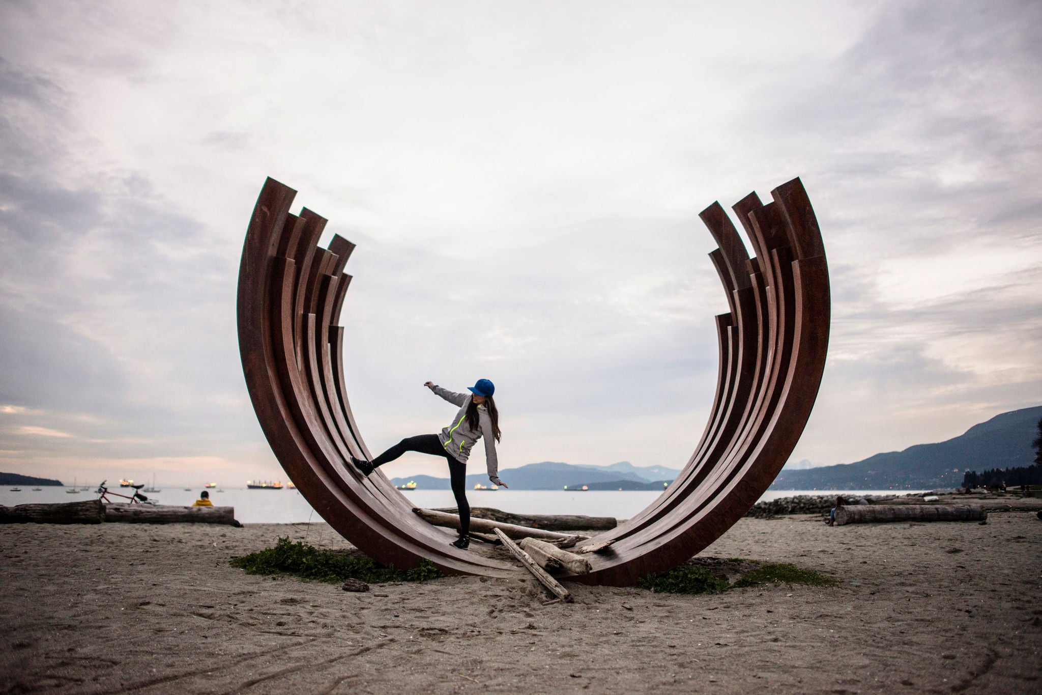 woman standing on arc sculpture, English bay, Vancouver, Canada