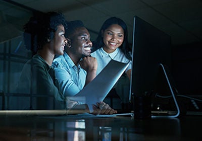 Doing what matters makes things happen. Shot of a group of young businesspeople using a computer together during a late night at work.