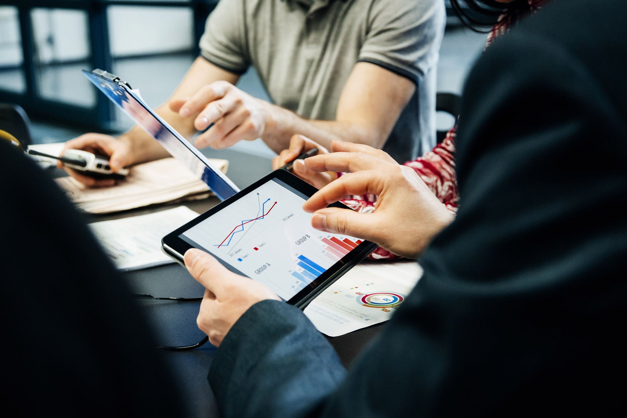 A close up of a printing factory management team holding a meeting and looking at data on digital tablets.