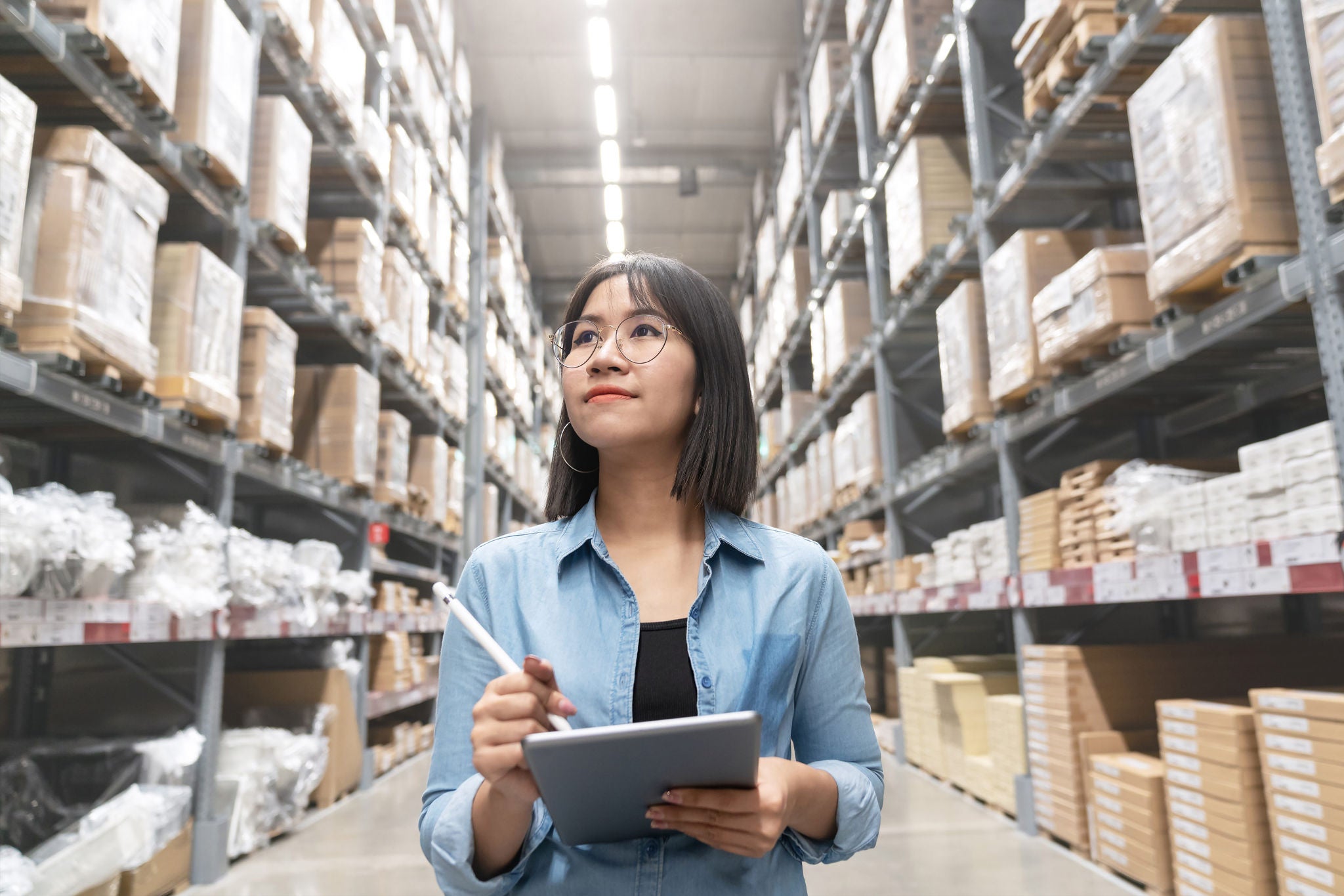 EY Woman looking Up Stock taking Inventory in Warehouse