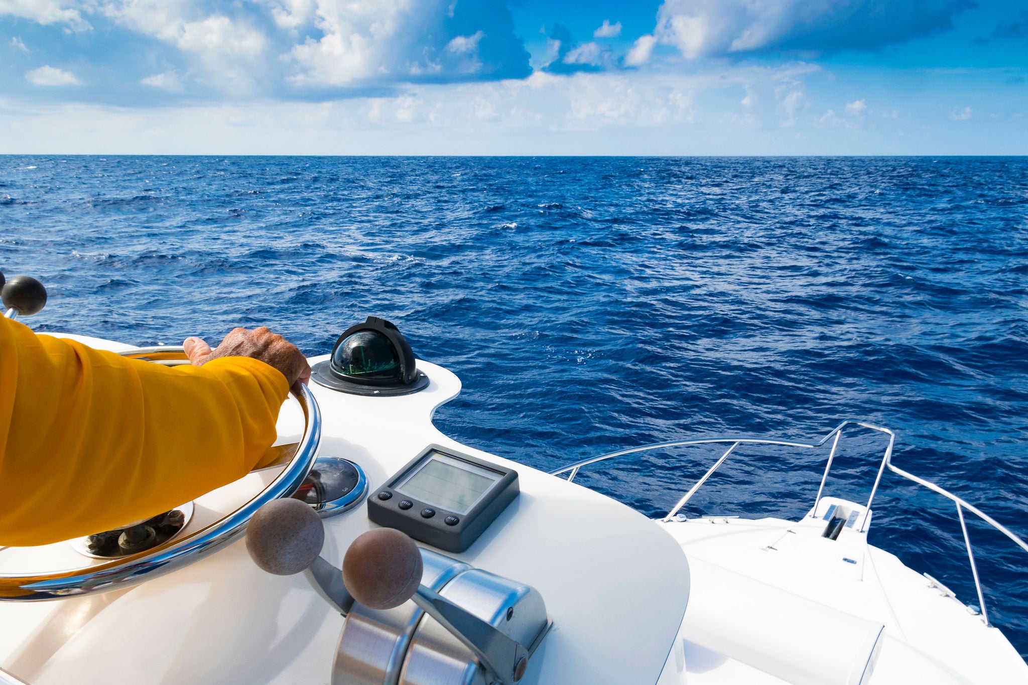 Hand of captain on steering wheel of motor boat in the blue ocean