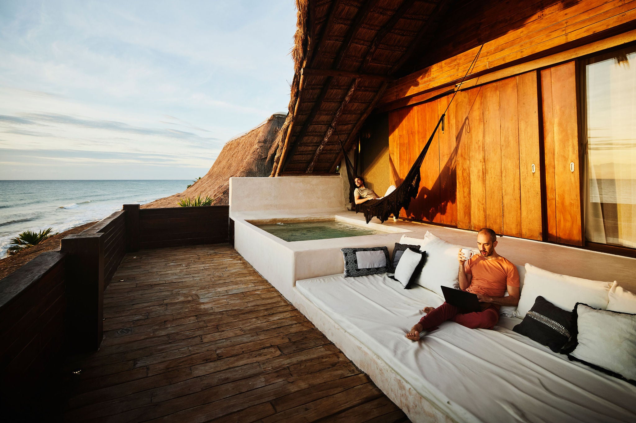 Man drinking coffee with partner in hammock