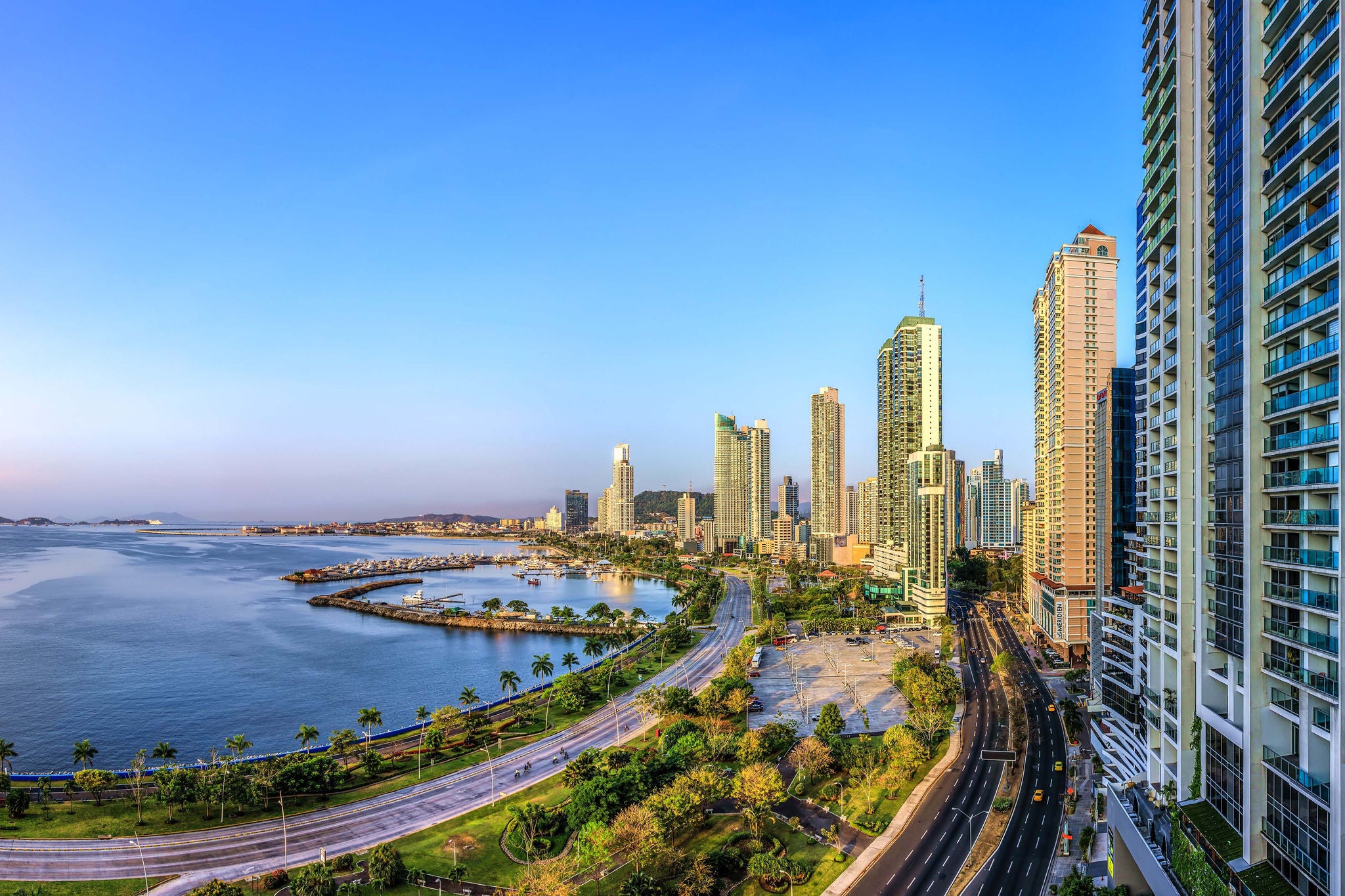 Panoramablick auf Panama City, hohe Gebaeude gegen blauen Himmel, vor blauem Meer.