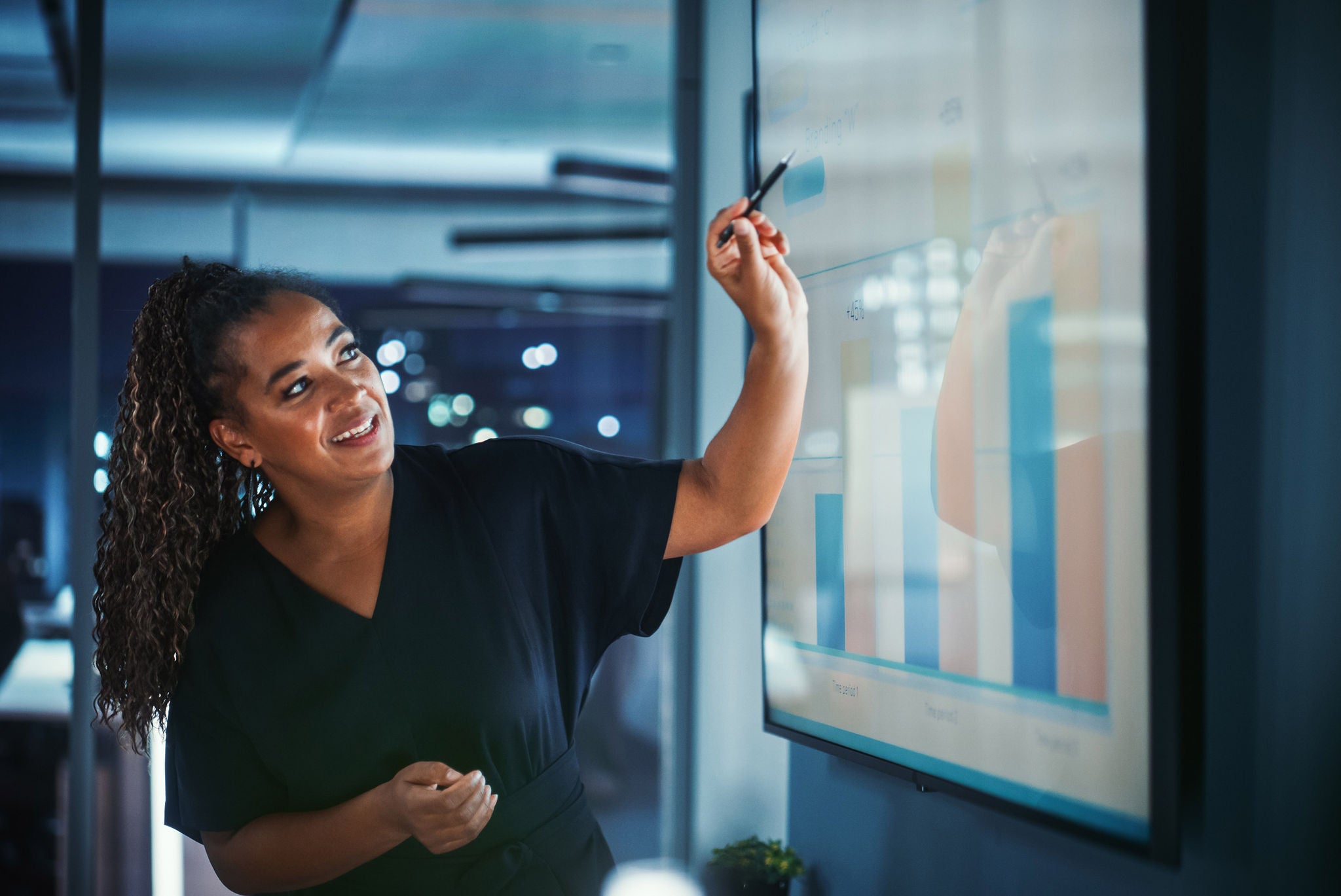 Company Operations Director Holds Sales Meeting Presentation for Employees and Executives. Creative Black Female Uses TV Screen with Growth Analysis; Charts; Ad Revenue. Work in Business Office.