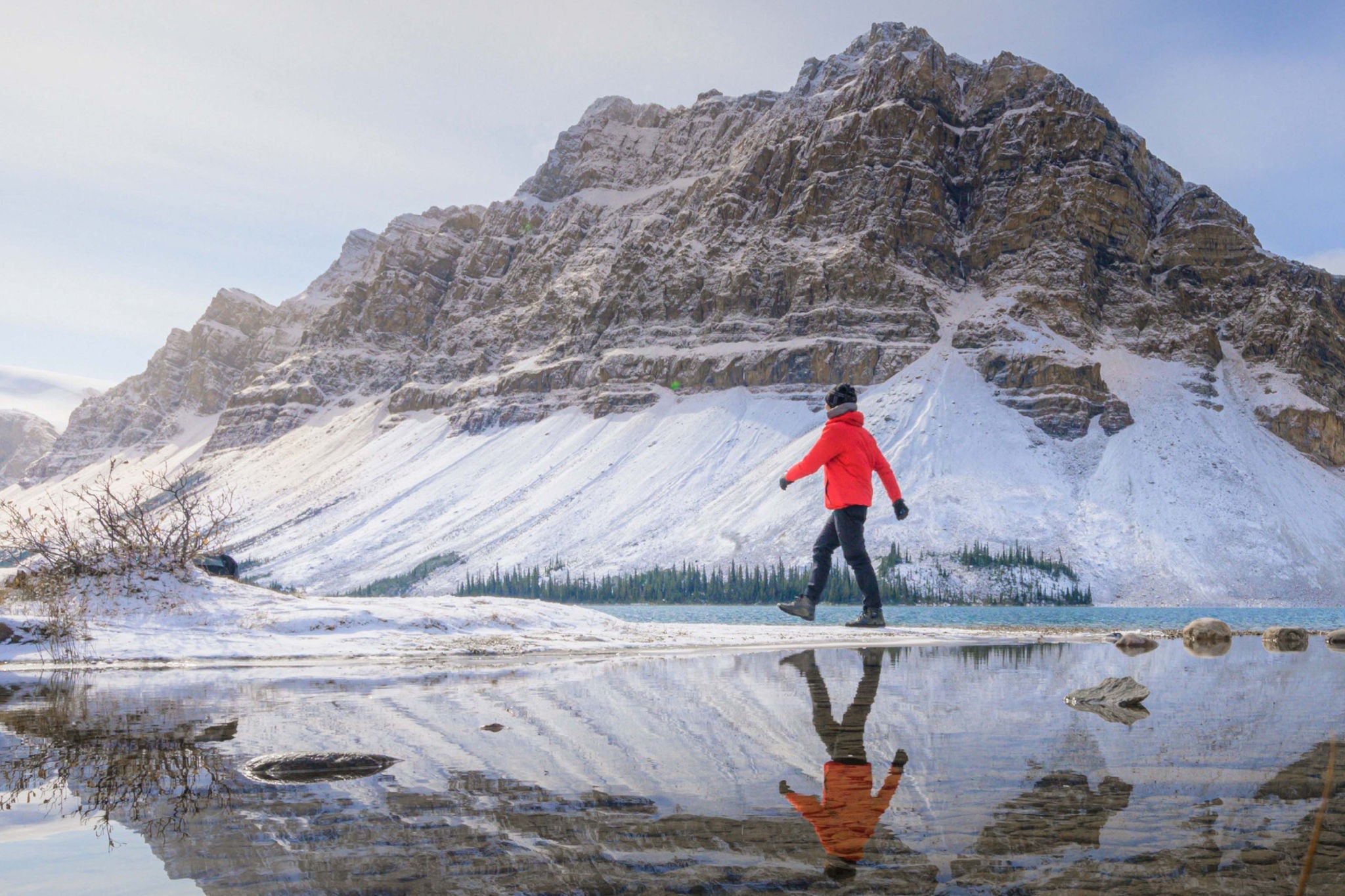 Person hiking by mountain with reflection