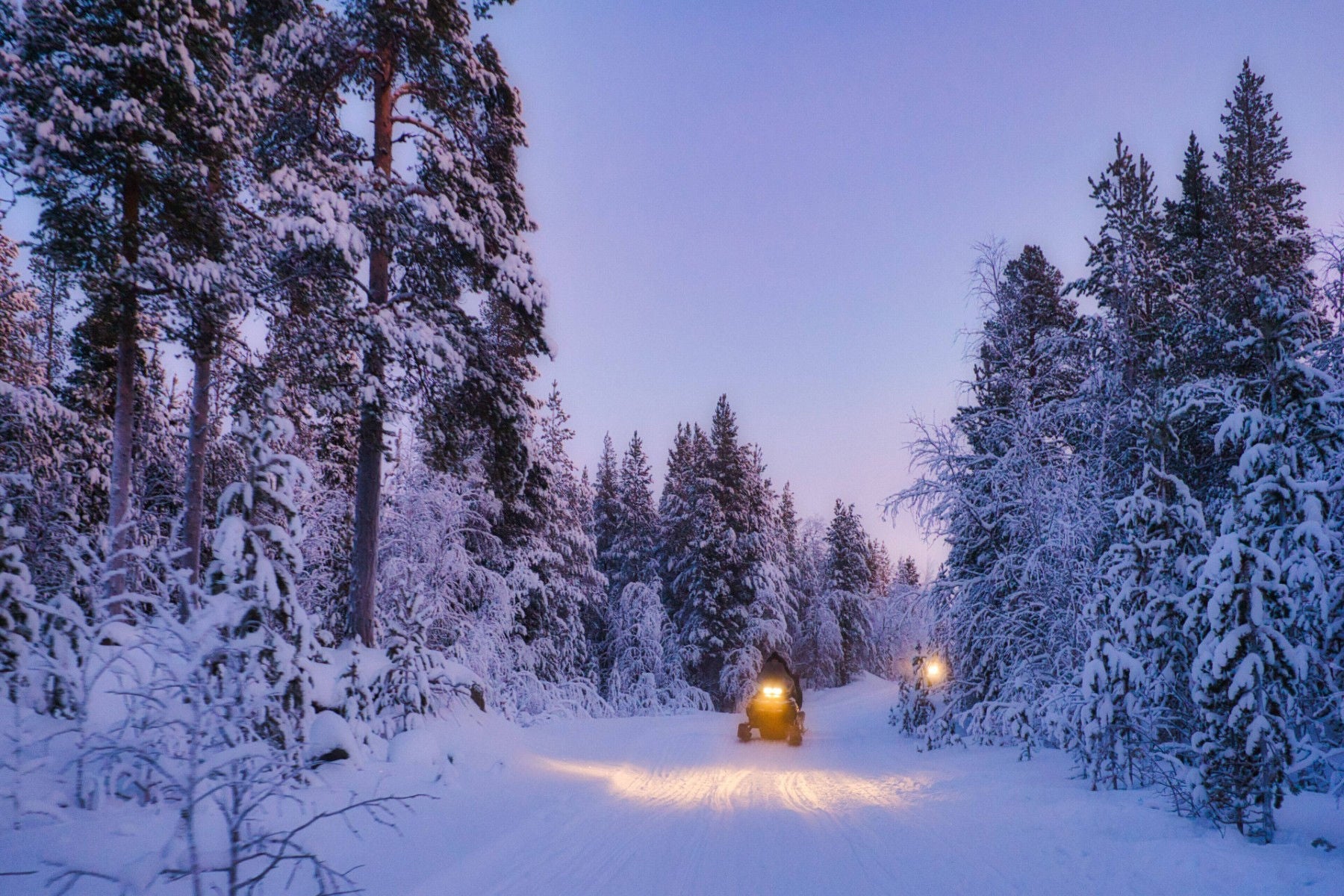 ey-two-people-riding-snowmobiles-through-a-snowy-landscape