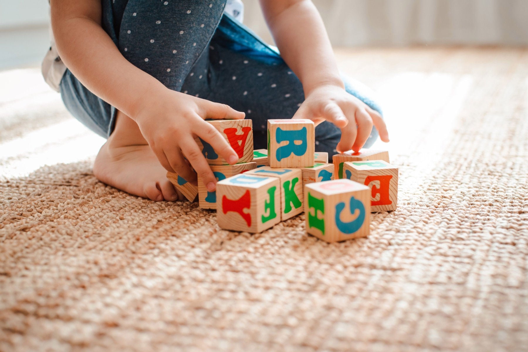 Child plays with wooden blocks with letters on the floor in the room