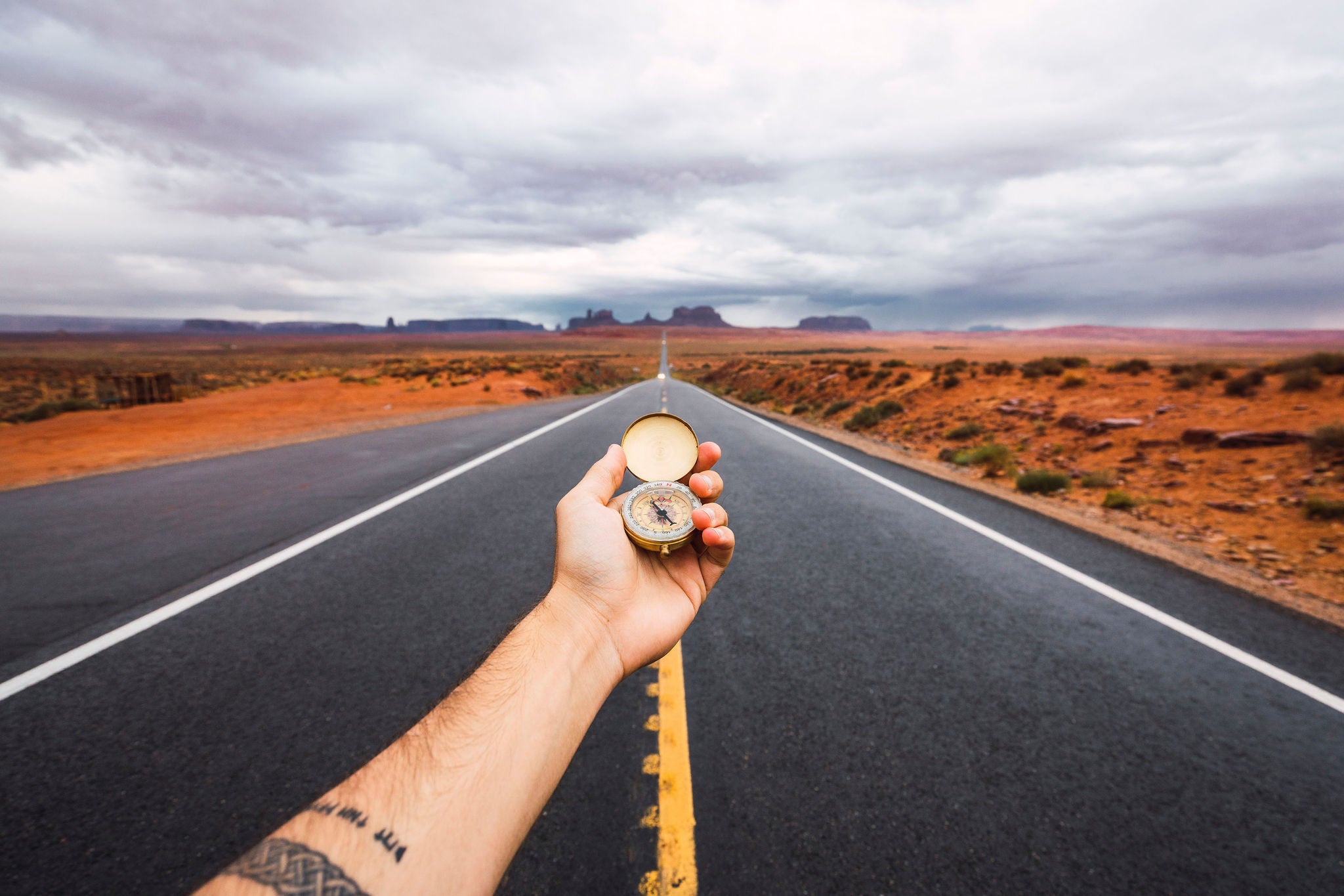 Eine Hand hÃ¤lt einen Kompass Ã¼ber die StraÃ e zum Monument Valley