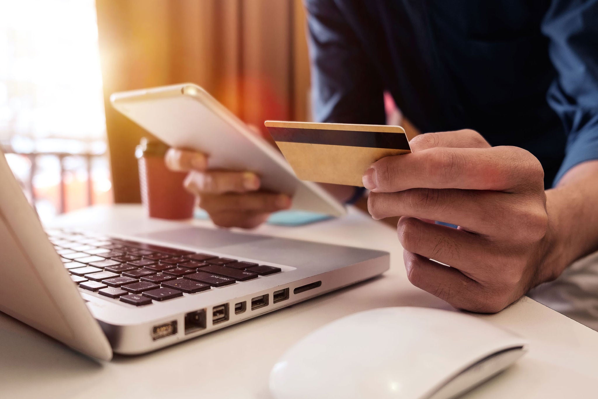 Person checking document, Credit card in one hand and laptop infornt  of him